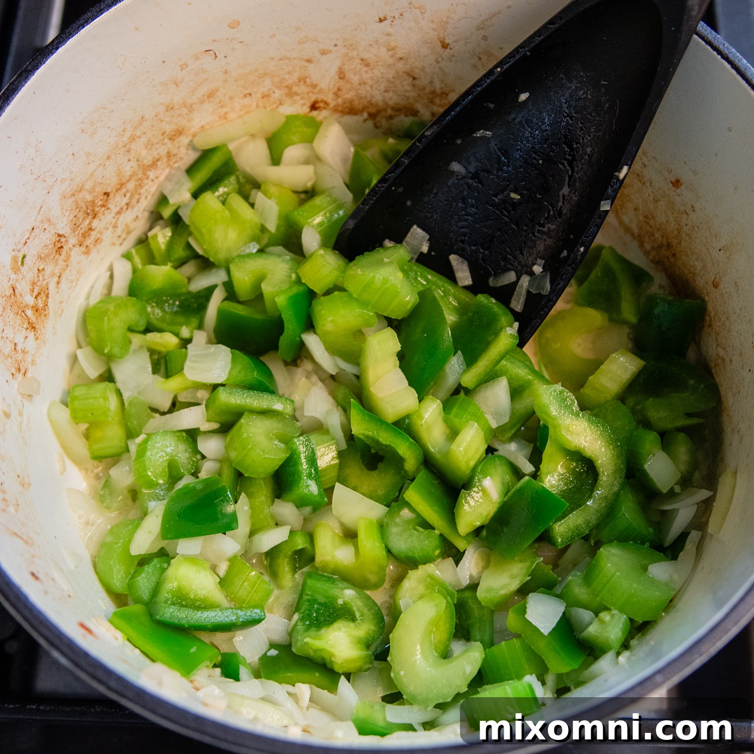 Onion, celery, and bell pepper (the holy trinity) sautéing in a pot.