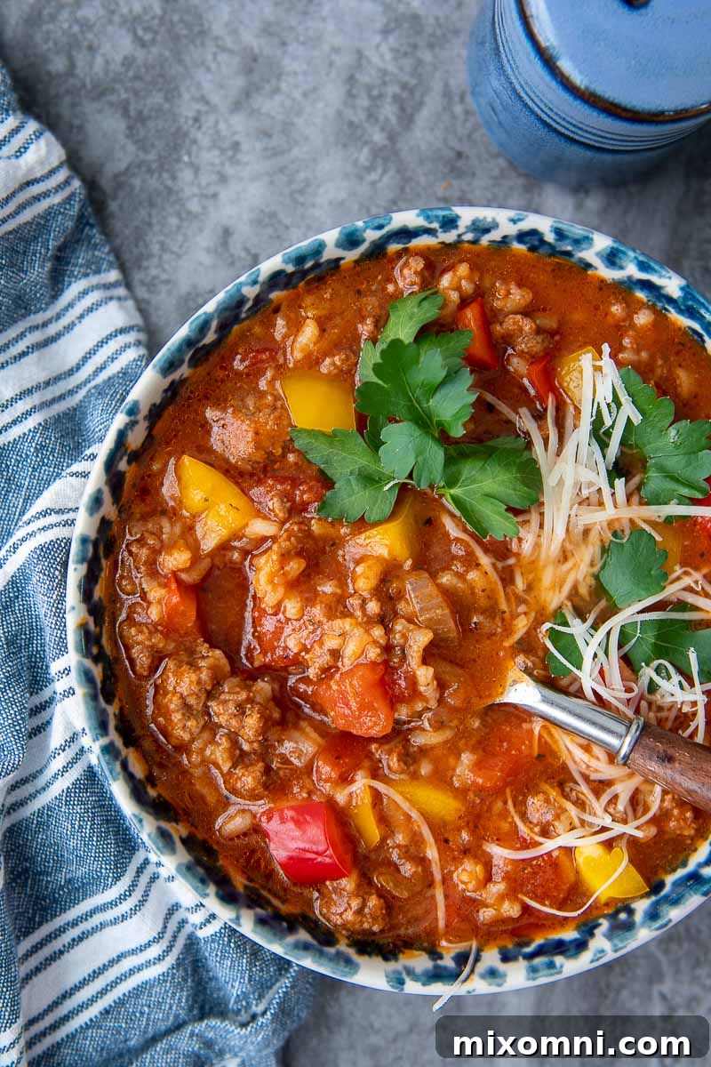 A spoon lifting out a spoonful of delicious stuffed pepper soup, highlighting the tender beef, rice, and colorful peppers.