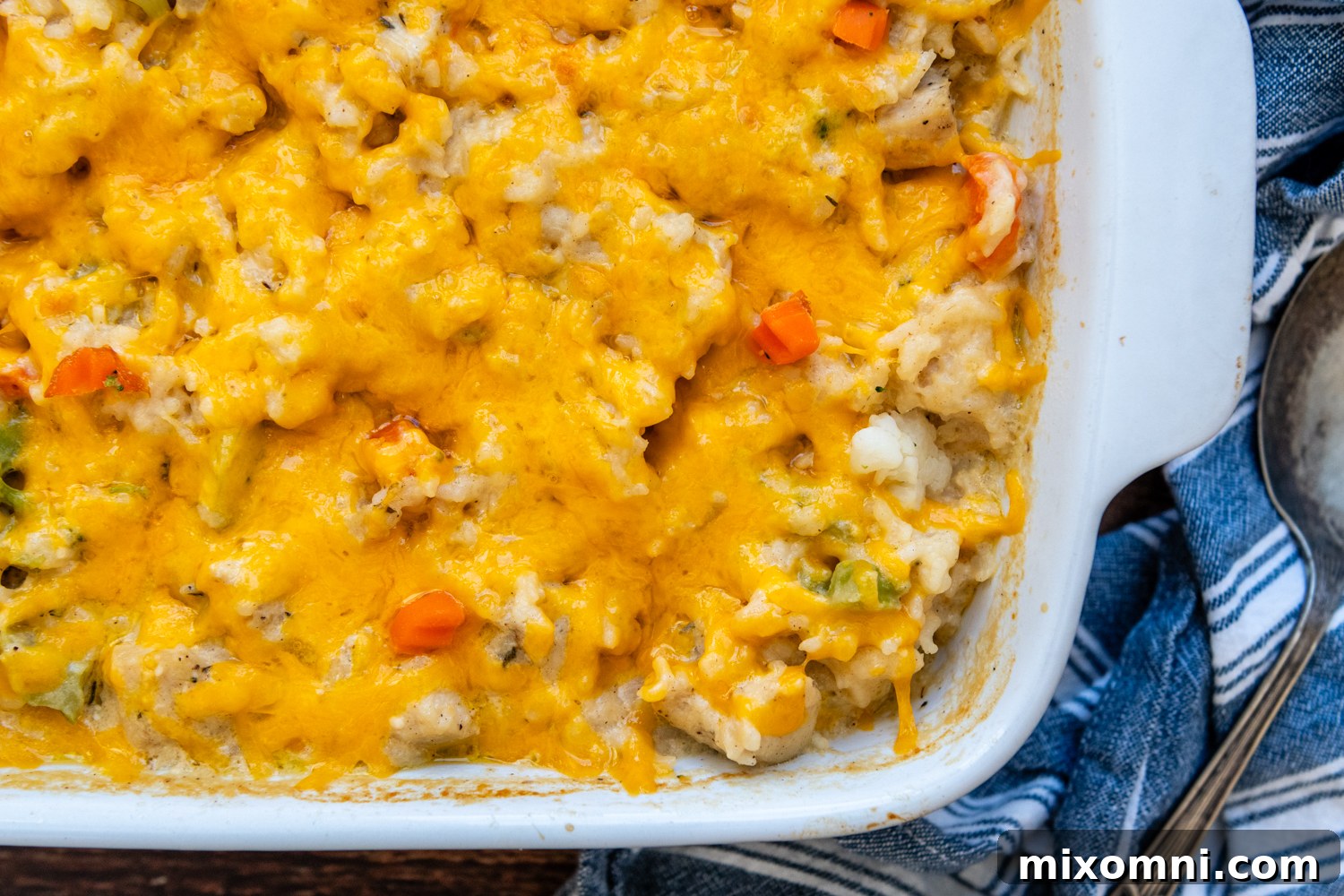 A white ceramic baking dish filled with a golden, bubbly Gluten-Free Chicken Rice Casserole, fresh from the oven, ready to serve.