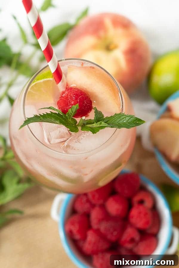 looking down on top of a raspberry peach mojito with fresh mint sprig and straw in the glass