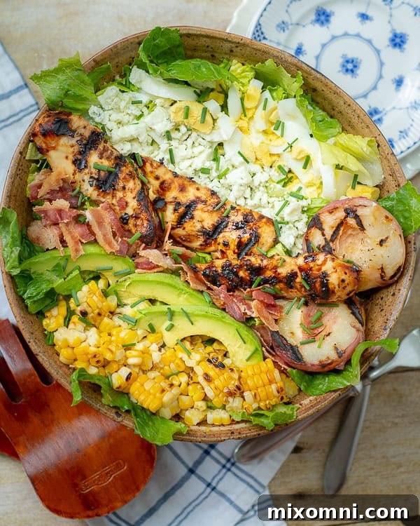 Overhead shot of two grilled chicken Cobb salads ready to be served, with additional plates in the background.