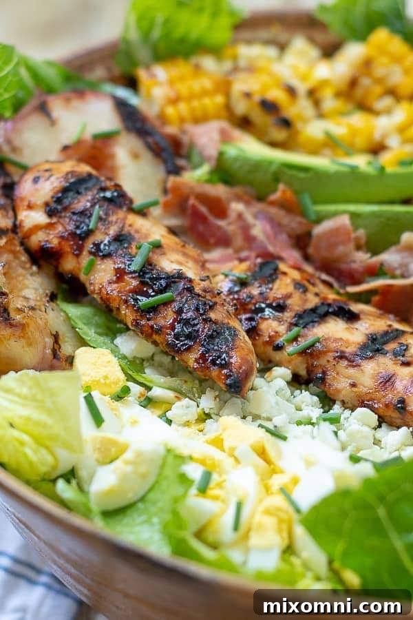 Close-up of a beautifully plated grilled chicken Cobb salad, showing intricate layers of ingredients.