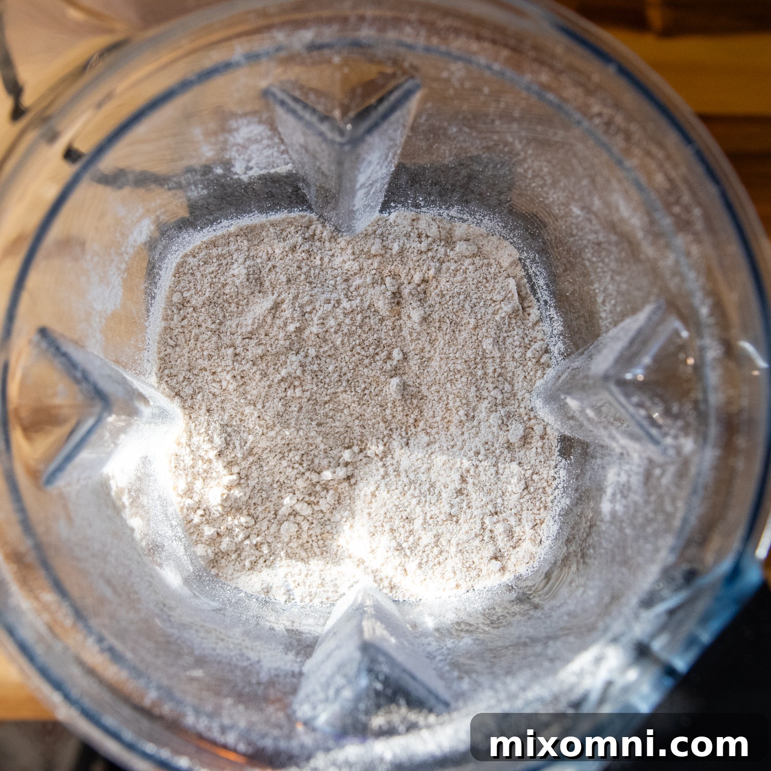 Rolled oats being blended into fine flour in a high-speed blender, demonstrating the first step in making oat flour carrot cake.