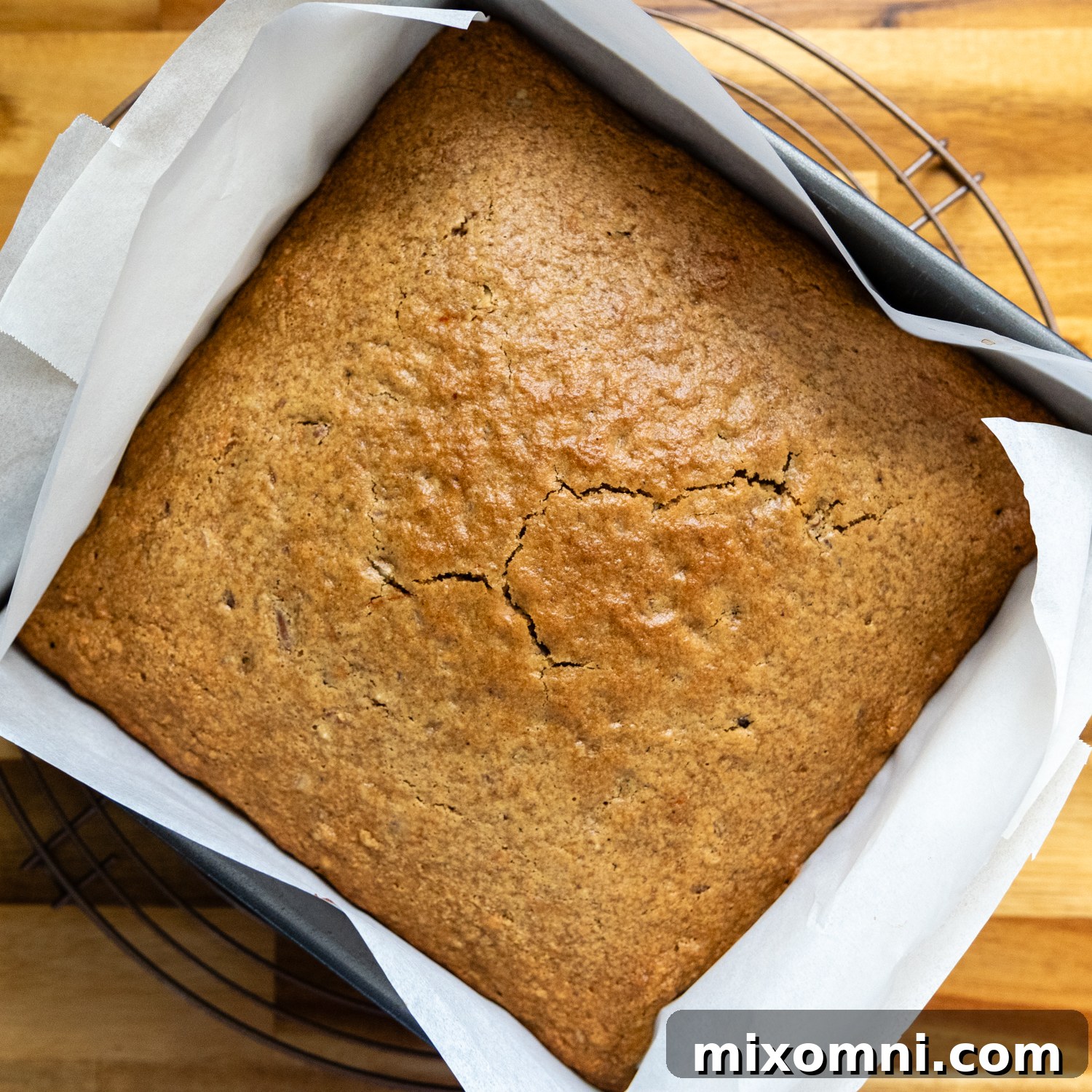 The carrot cake batter, baked to golden perfection, sitting in a square baking pan, ready for cooling.