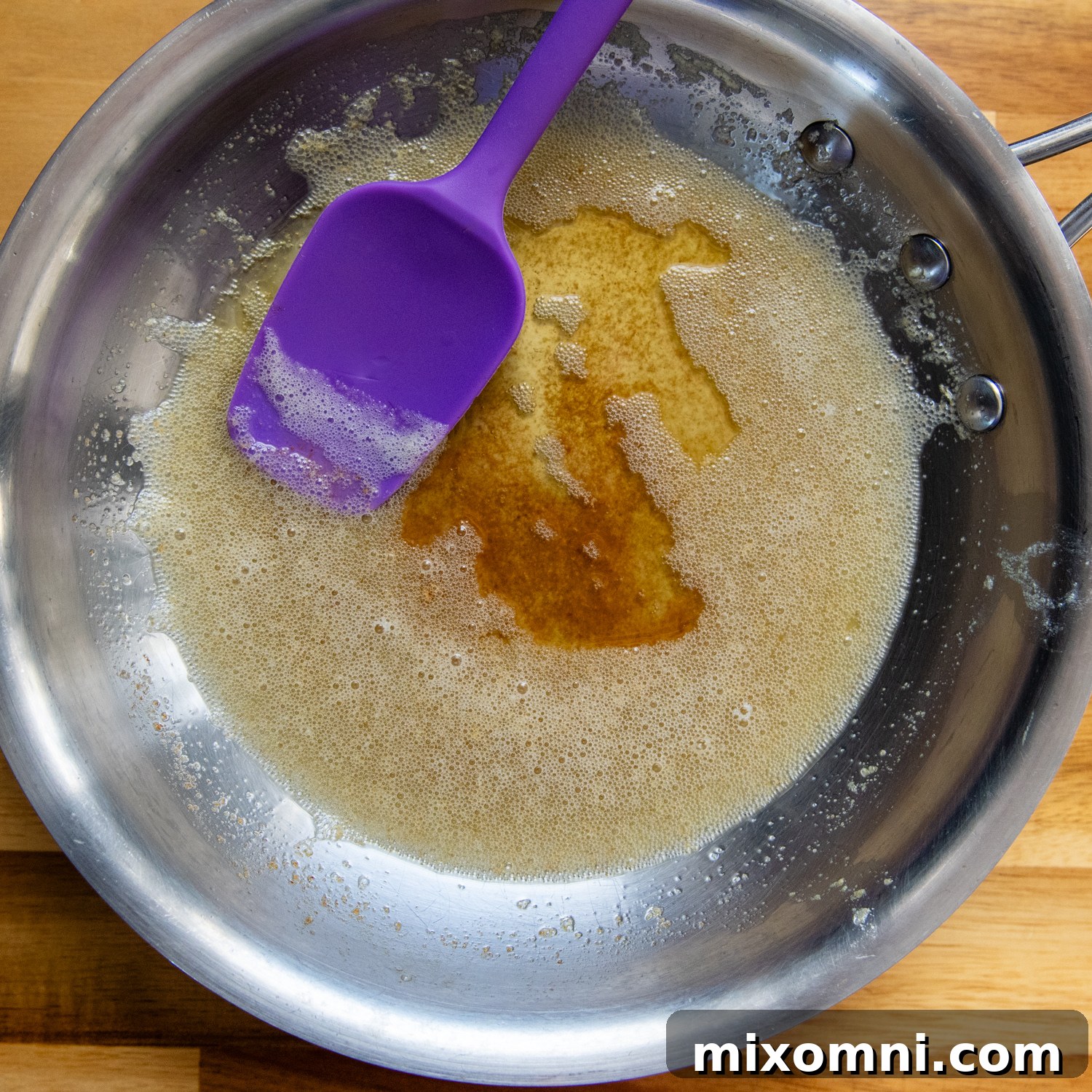 Ingredients for browned butter cream cheese frosting, including browned butter, cream cheese, and powdered sugar, in a mixing bowl.