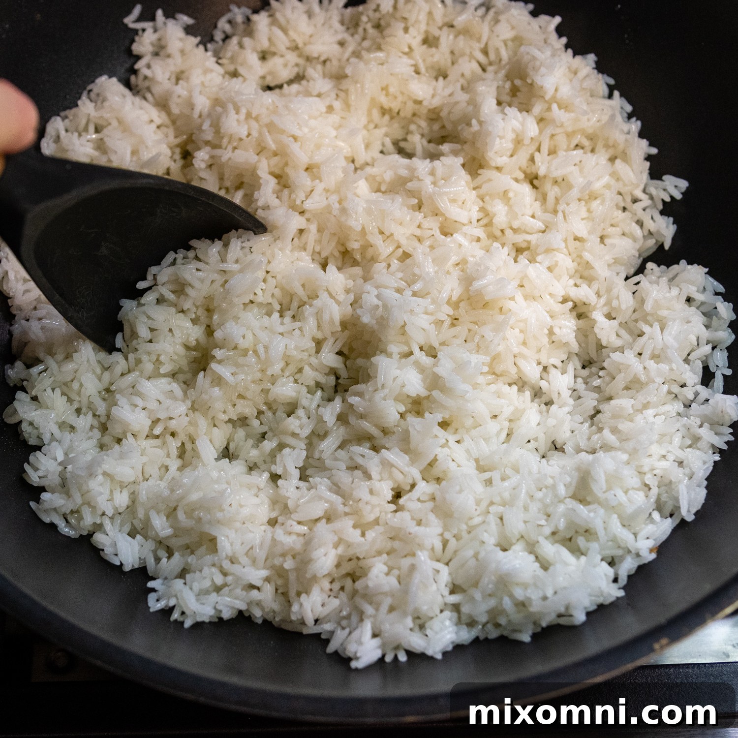 Perfectly prepared, cold jasmine rice sitting in a black bowl, ready to be added to the wok for frying.