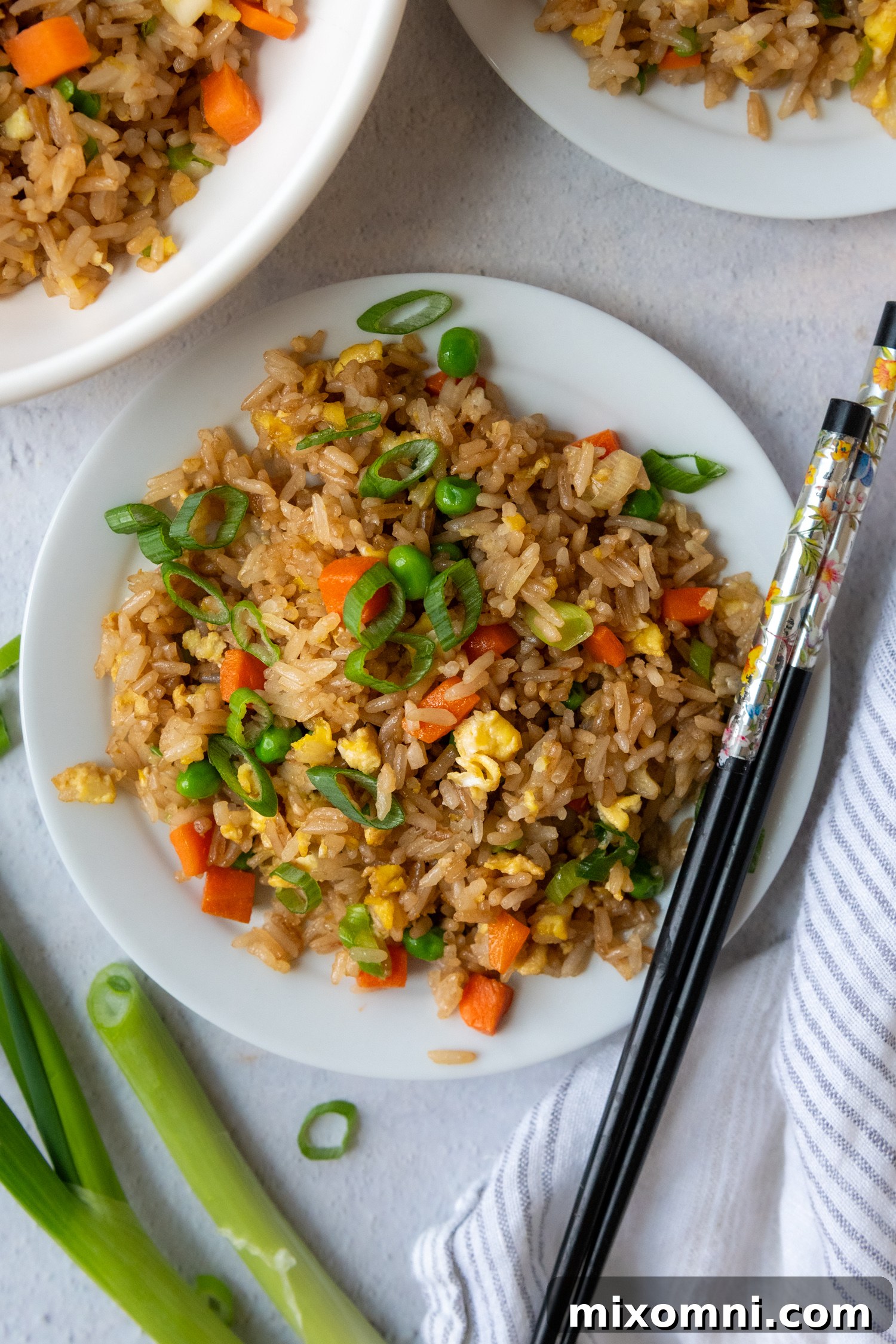 A beautifully plated gluten-free fried rice dish on a white plate, accompanied by a pair of elegant chopsticks, inviting a delightful meal.