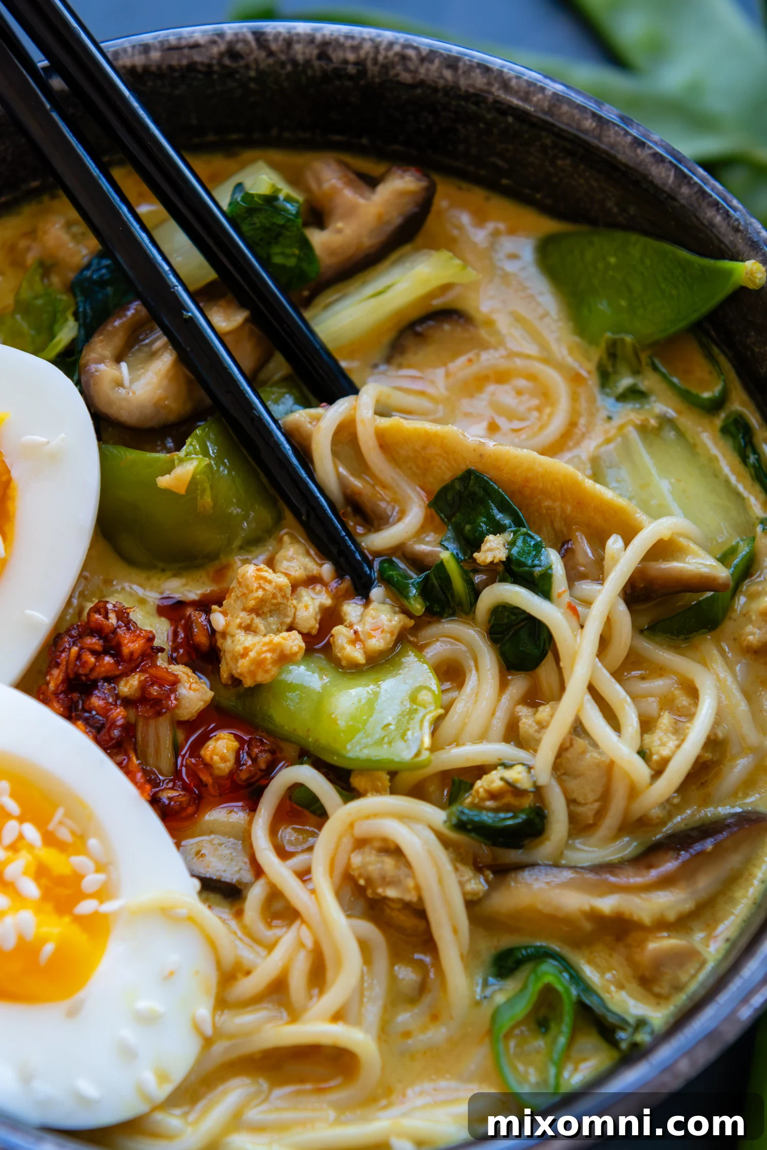 Chopsticks in a bowl with gluten-free ramen and assorted toppings.