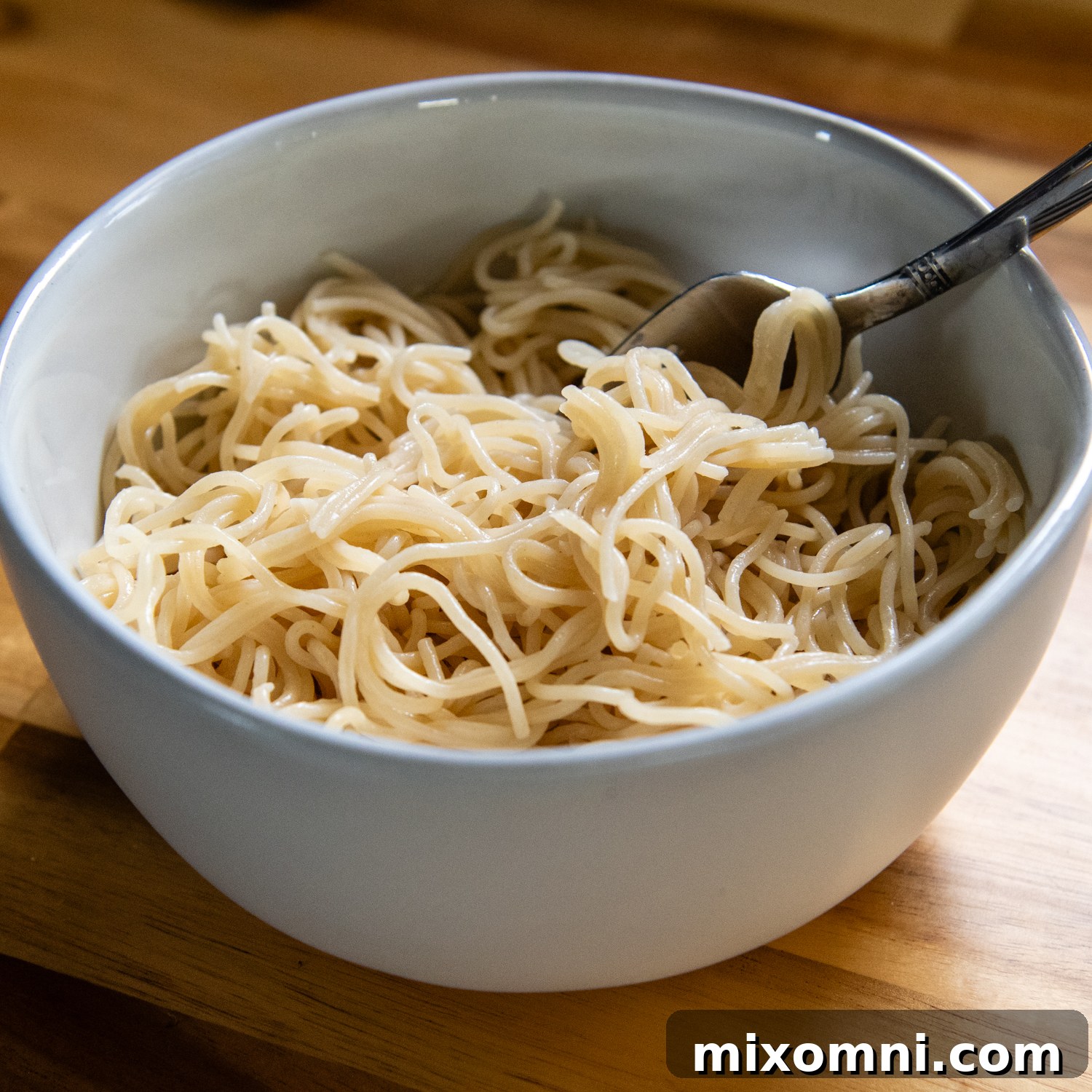 White bowl of ramen noodles with a spoon.