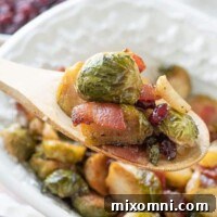 A wooden spoon lifting out a scoop of bacon Brussels sprouts from a serving dish.