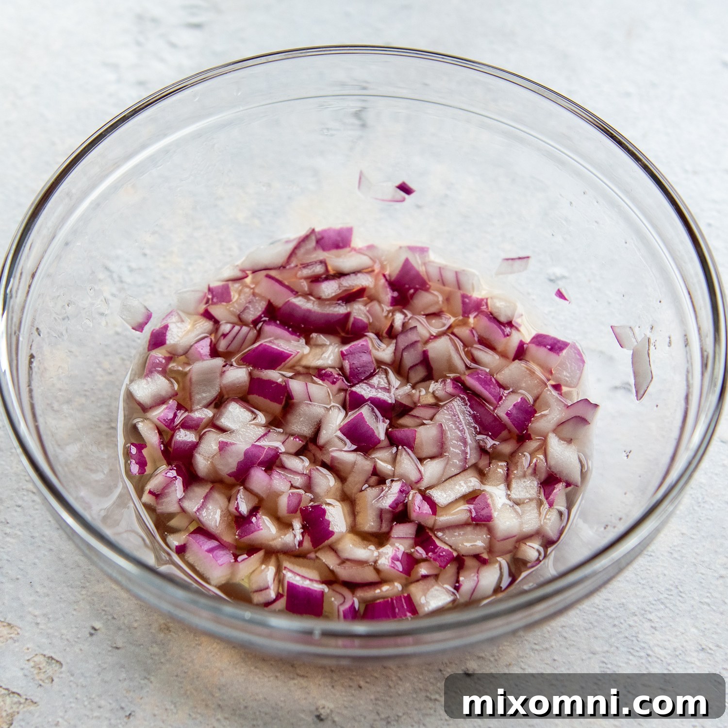 Glass bowl of red onions pickling.