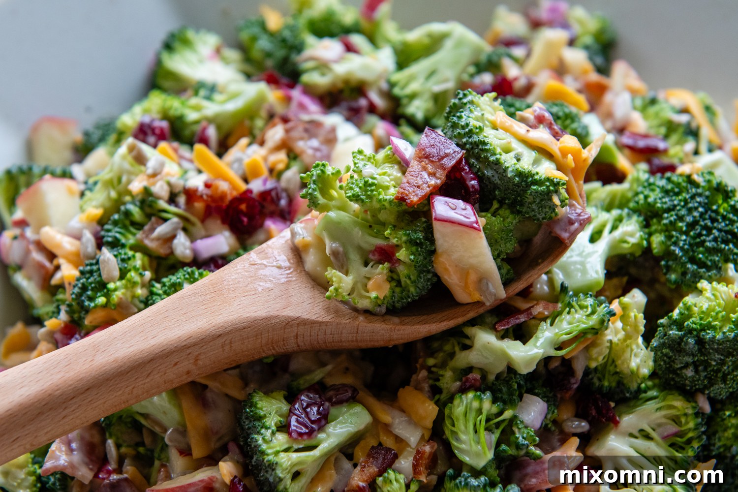 Wooden spoon scooping up a serving of the gluten-free broccoli salad.