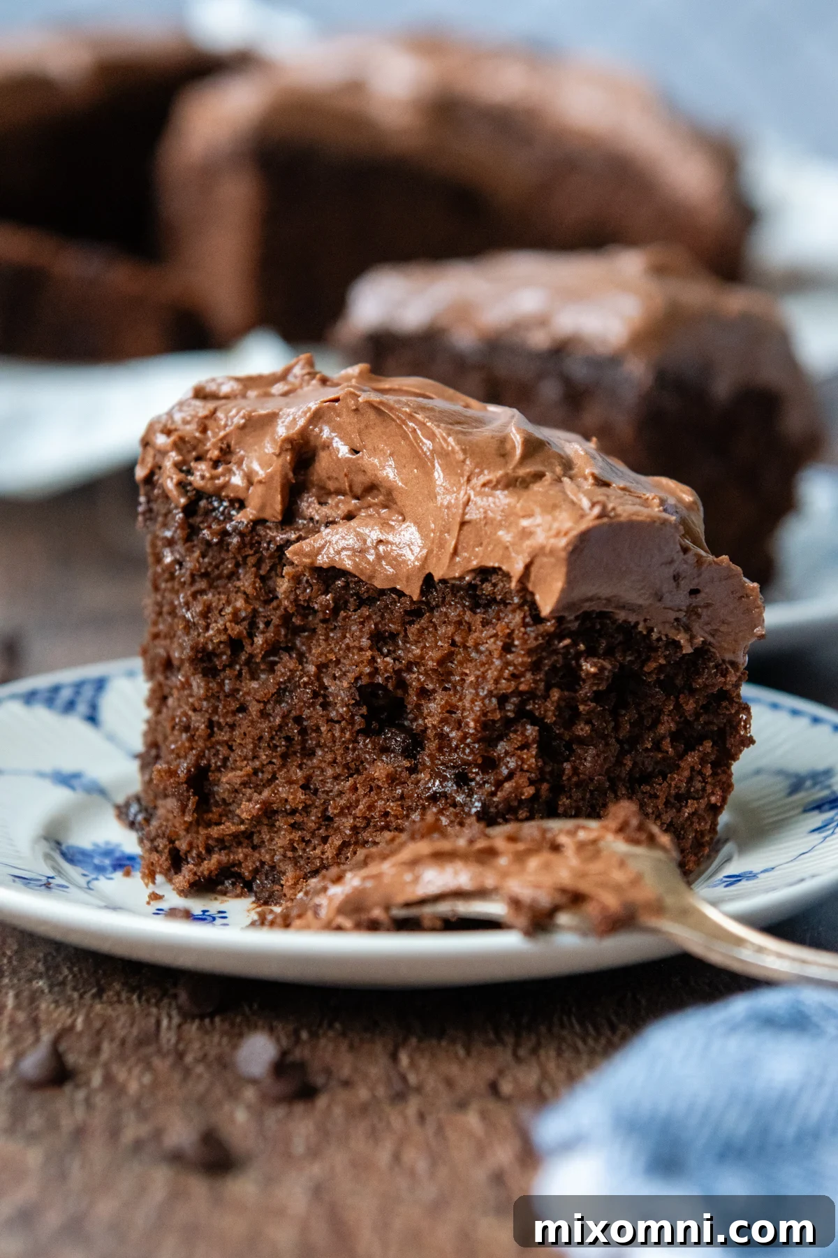 A perfectly sliced piece of moist oat flour chocolate cake on a plate, ready to be enjoyed with a fork.