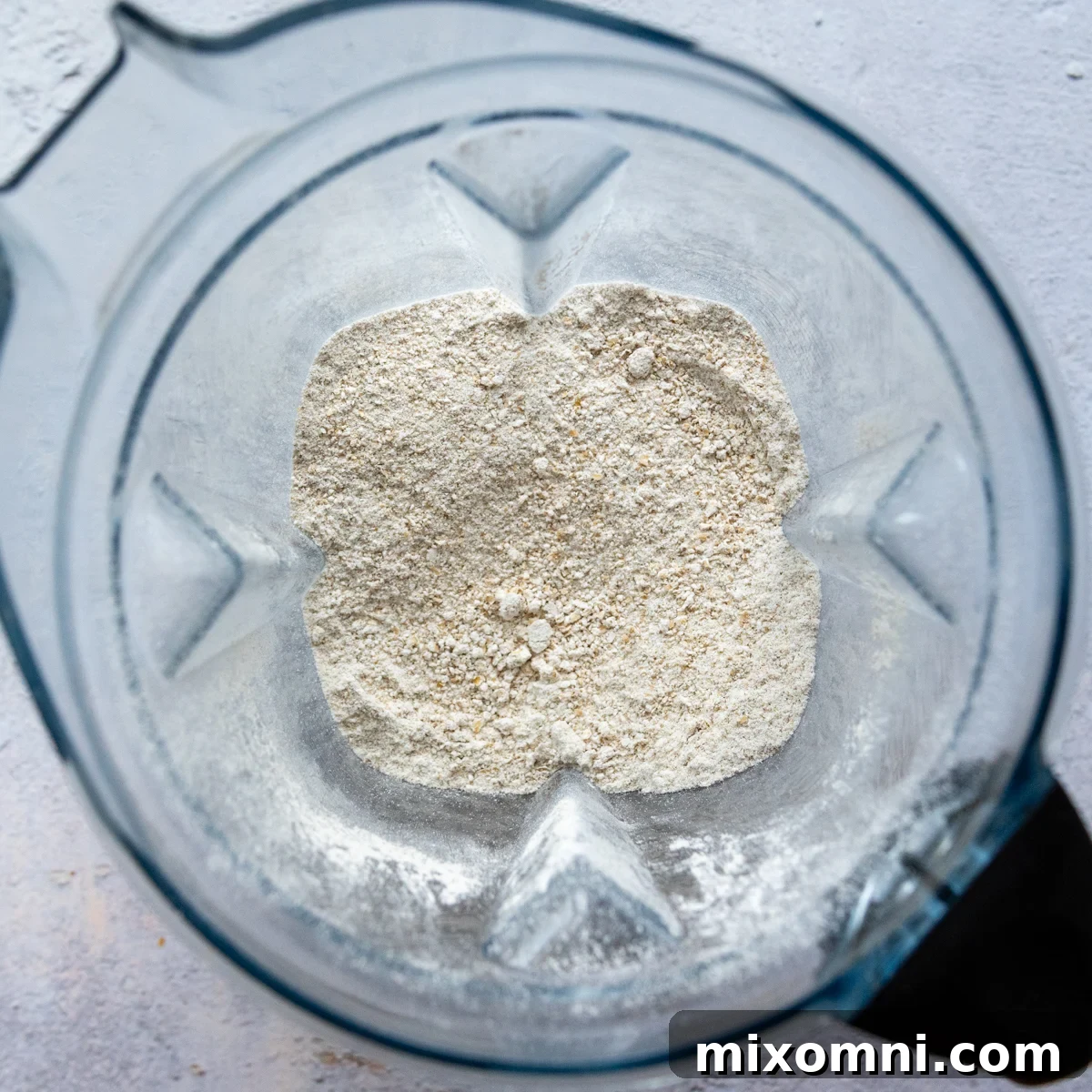 Dry ingredients for oat flour chocolate cake in a blender, showing the oats before blending into flour.