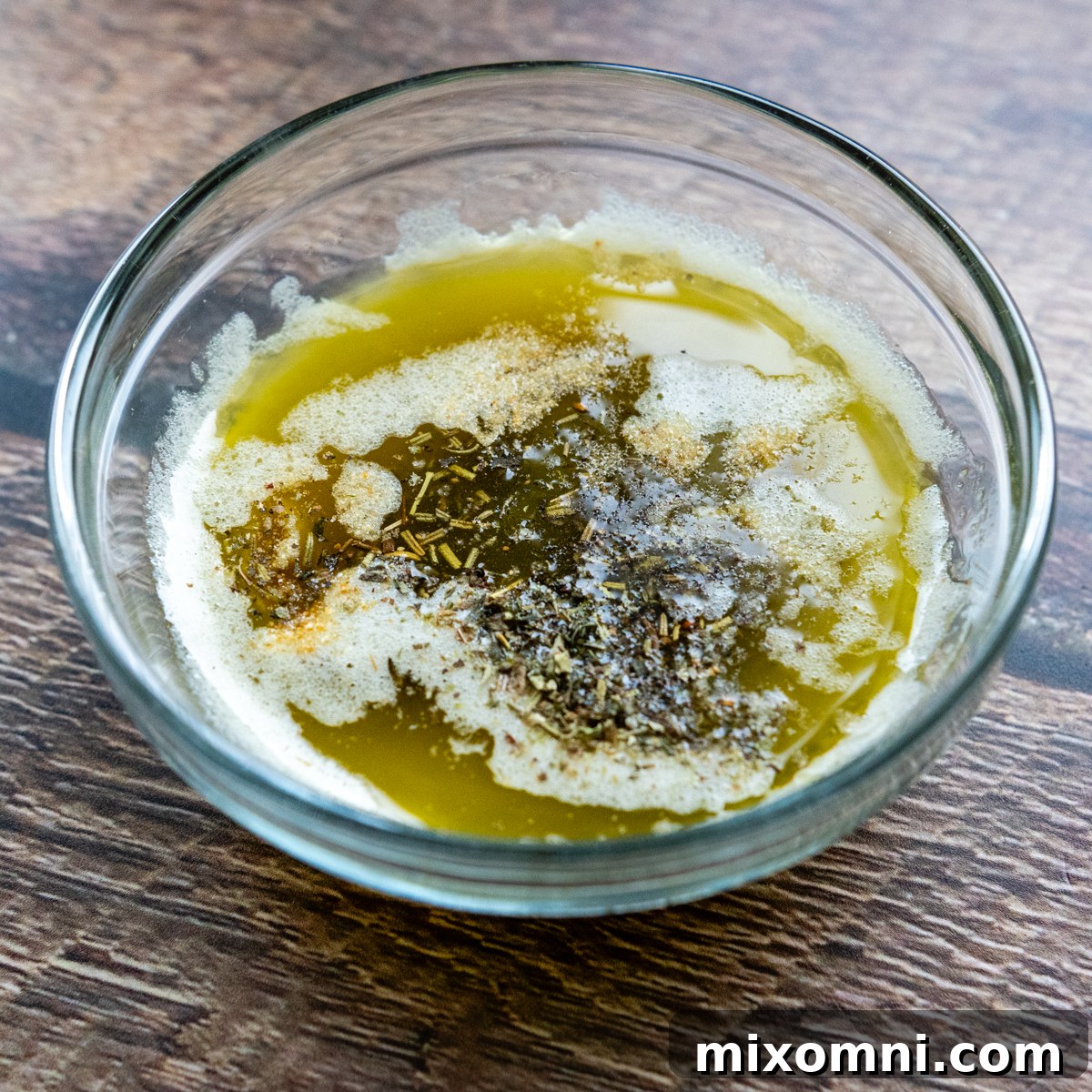 Melted butter, olive oil, and a blend of garlic powder, Italian seasoning, kosher salt, and black pepper whisked together in a glass bowl.