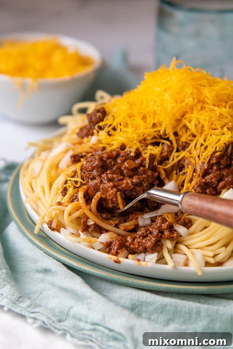 a fork going into chili topped spaghetti on a blue plate
