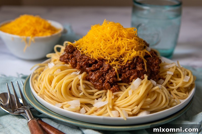 a plate of skyline chili on spaghetti with lots of cheese on top