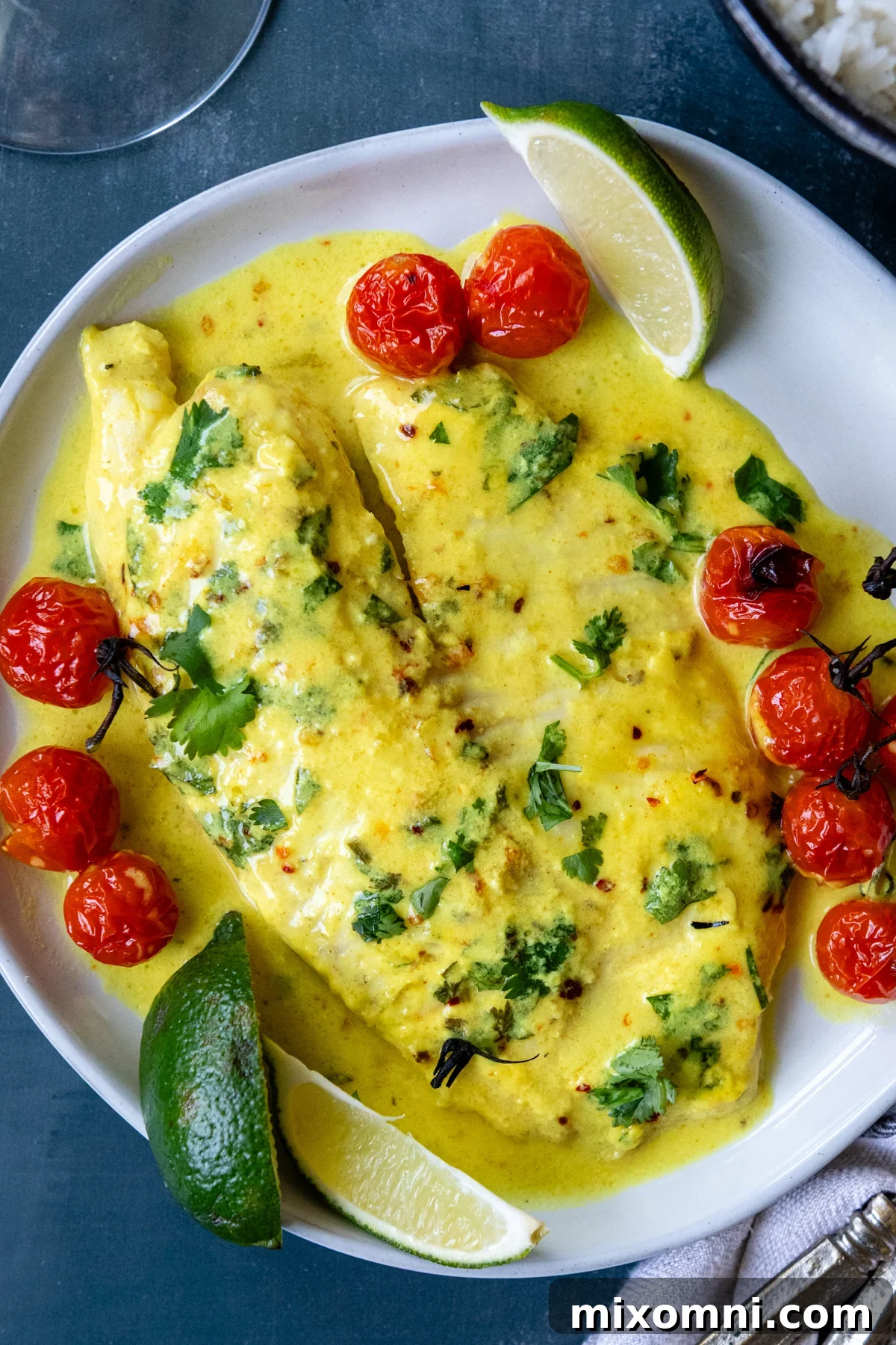 Fish on a white plate garnished with tomatoes and fresh herbs.