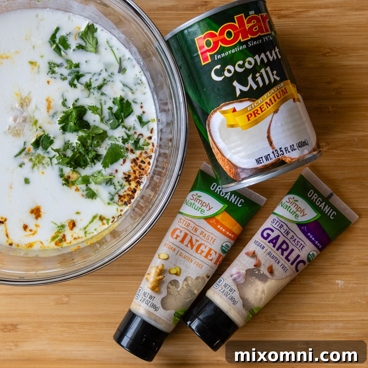 Individual ingredients for the coconut fish marinade, including coconut milk, lime, ginger, garlic, turmeric, honey, and red pepper flakes.