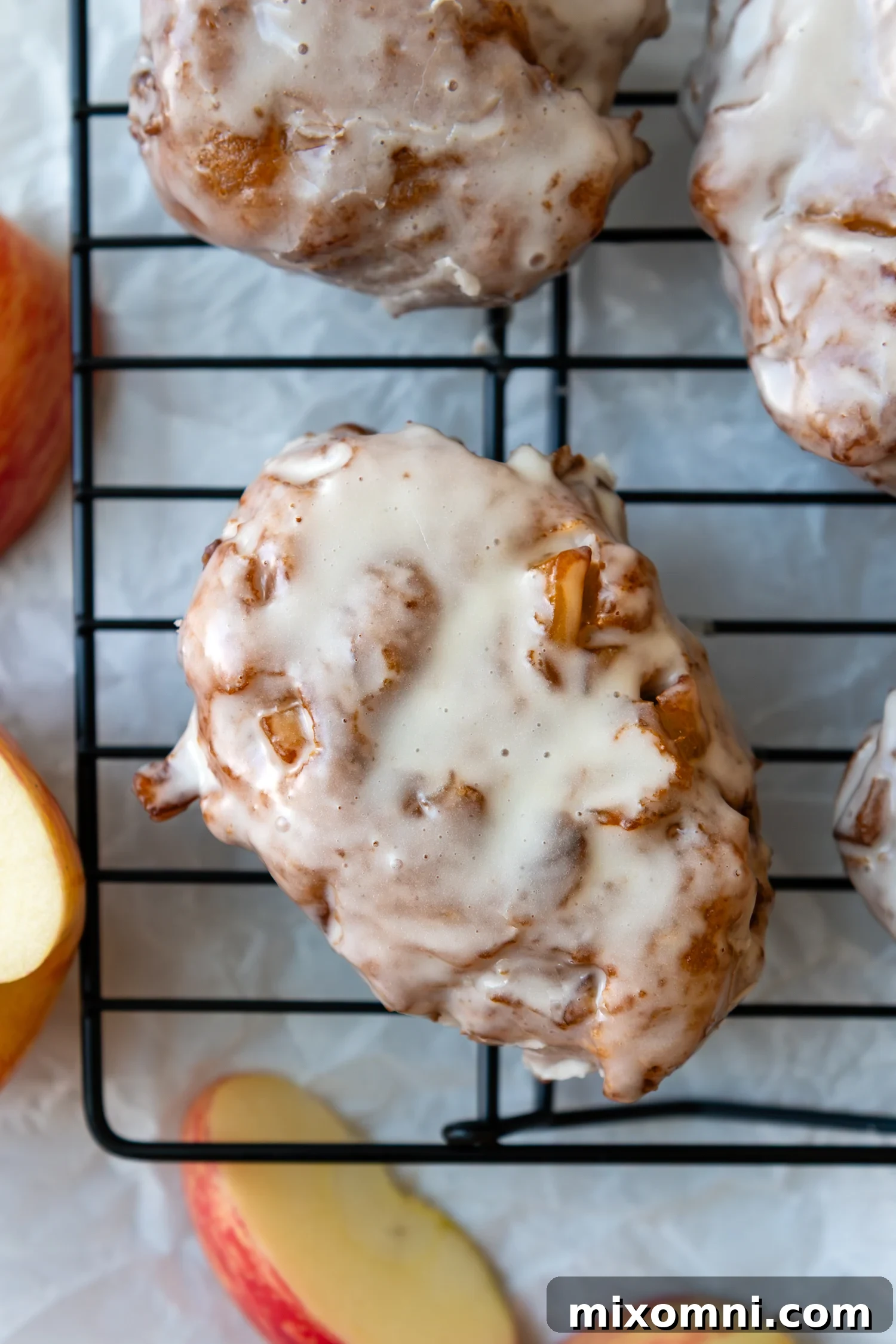 Gluten free apple fritter covered in glaze sitting on a drying rack.