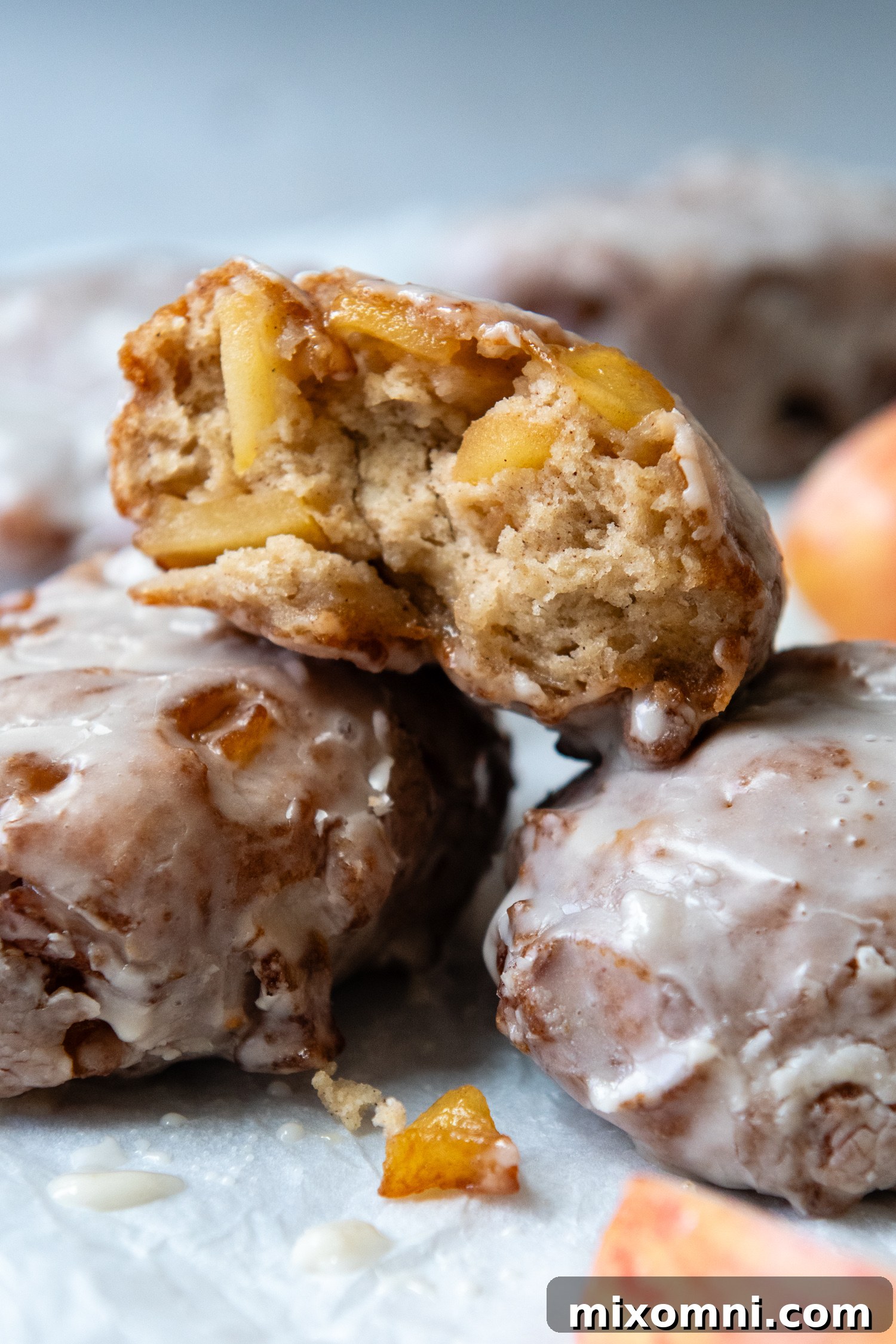 3 apple fritters piled on one another with one showing the inside texture.