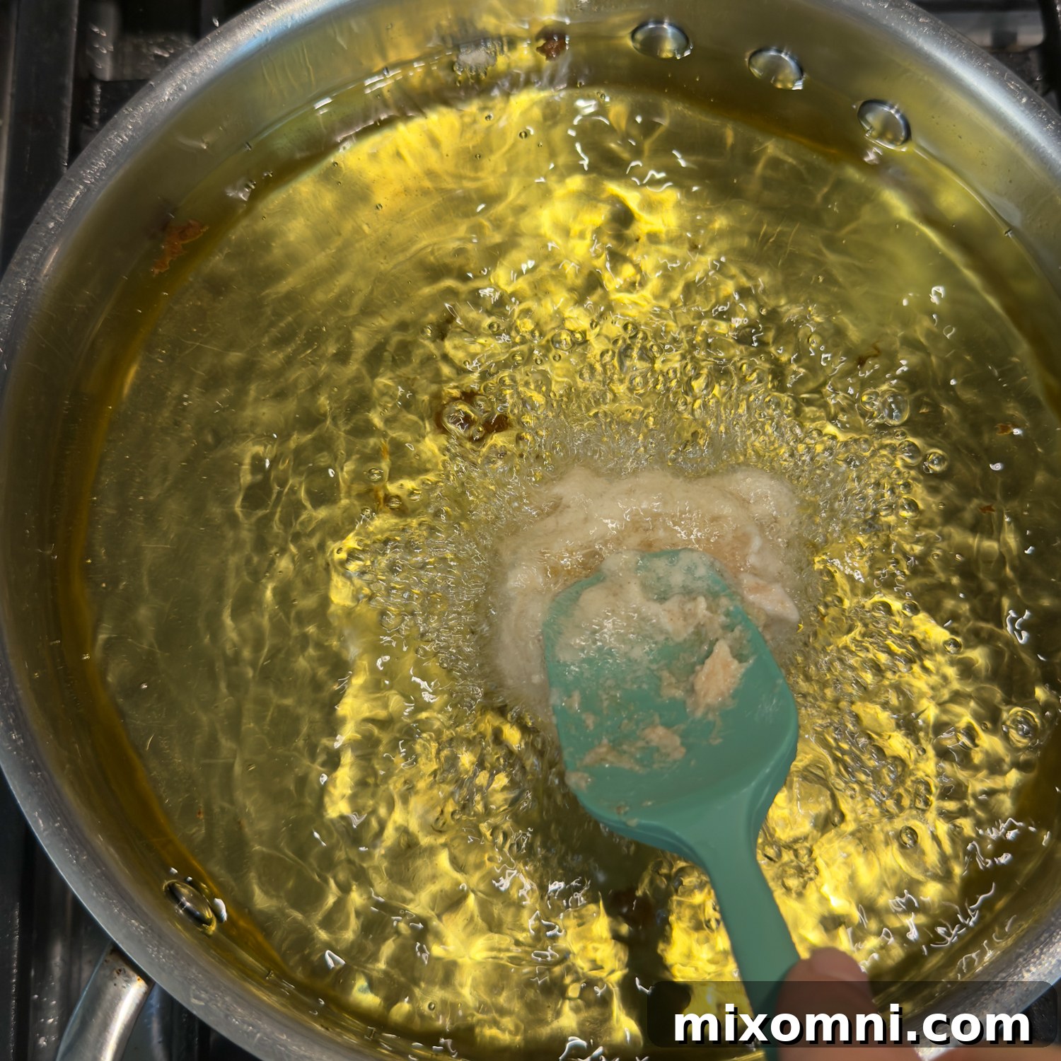 Blue spatula dropping in a doughy fritter.