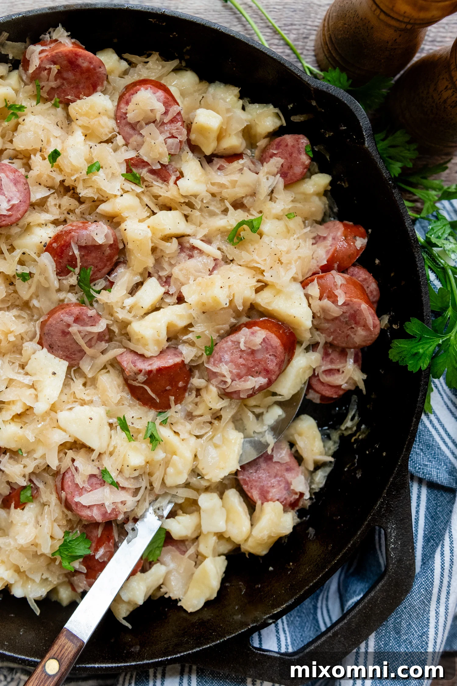 Hearty gluten-free dumplings and sausage served with sauerkraut in a rustic cast iron skillet.