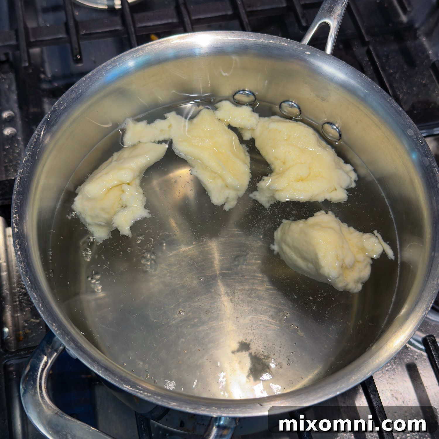 Gluten-free dumpling dough simmering in a pot of boiling water, visually indicating they are cooking.
