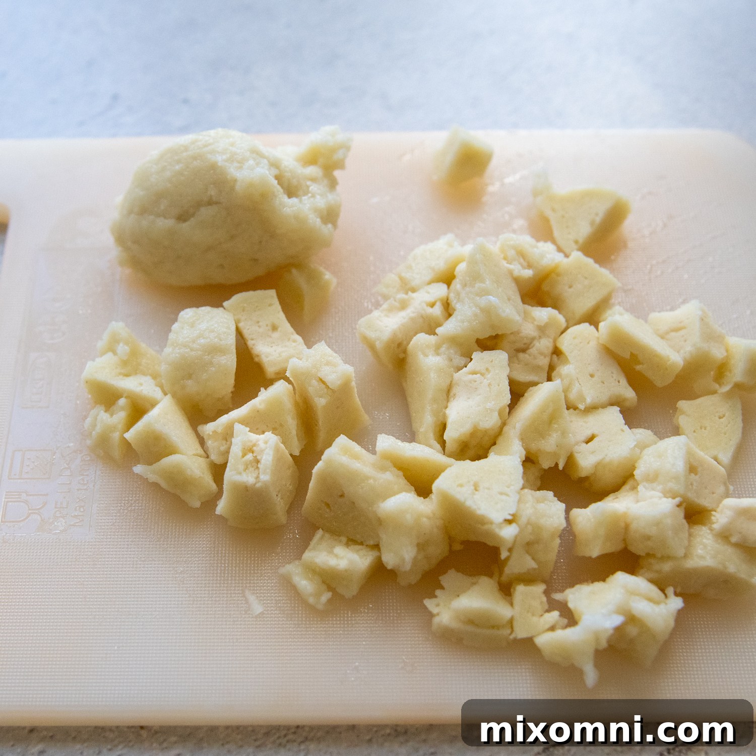 Cooked gluten-free dumplings, chopped into bite-sized pieces on a wooden cutting board.