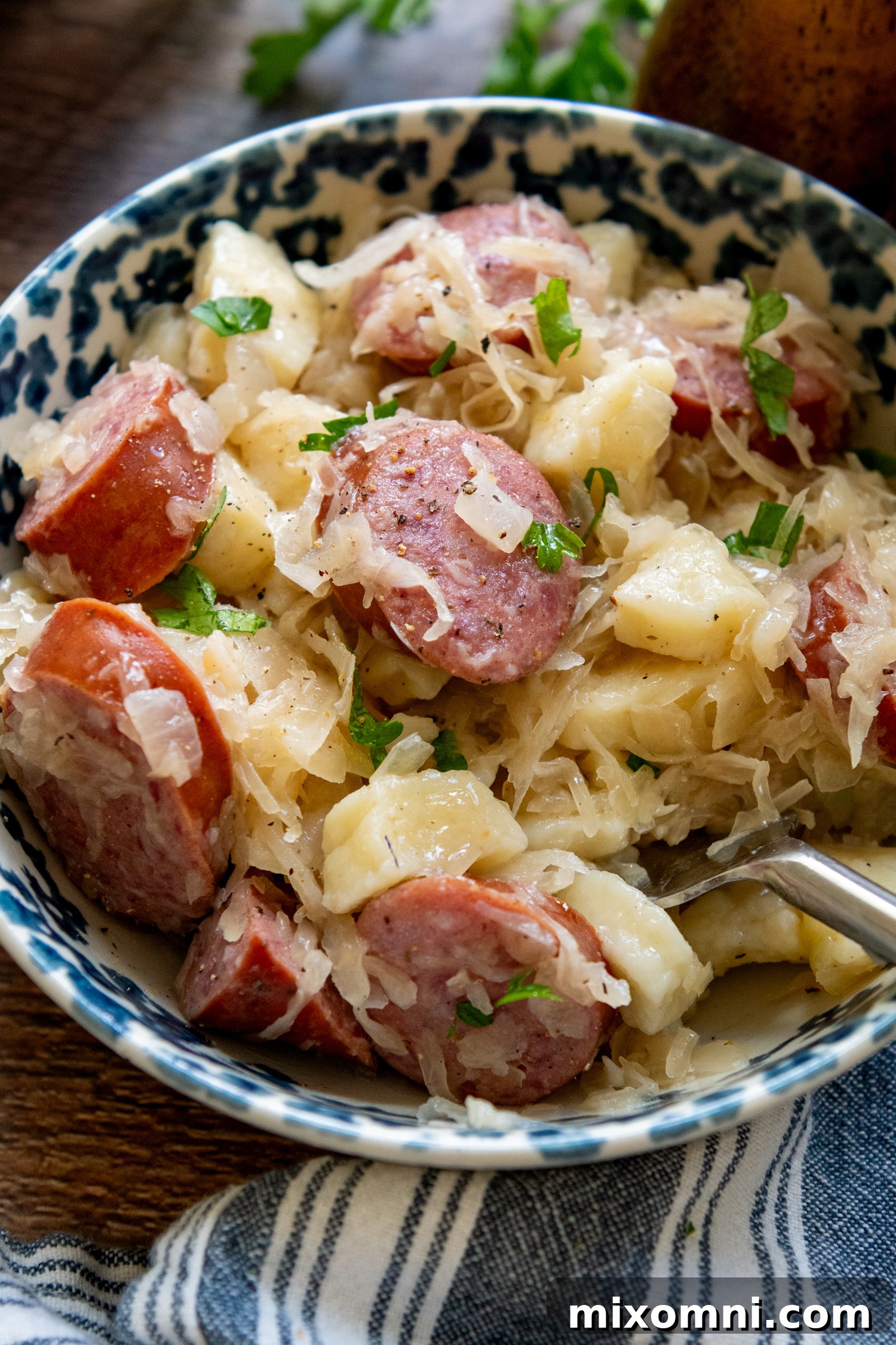 A serving of gluten-free dumplings and sausage with sauerkraut, perfectly plated in a bowl with a spoon.