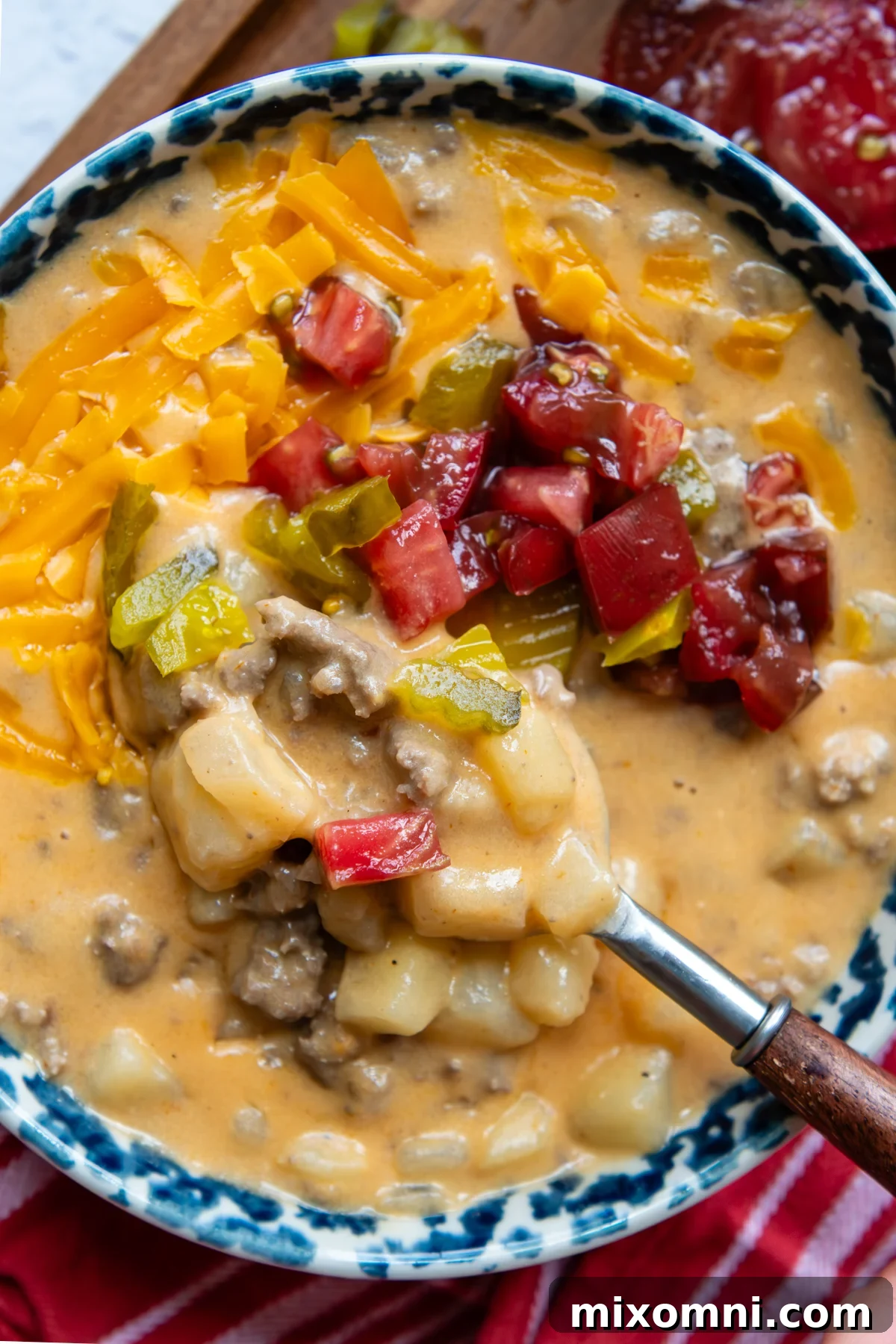 Overhead shot of gluten free cheeseburger soup in a bowl with a spoon, garnished with fresh herbs.