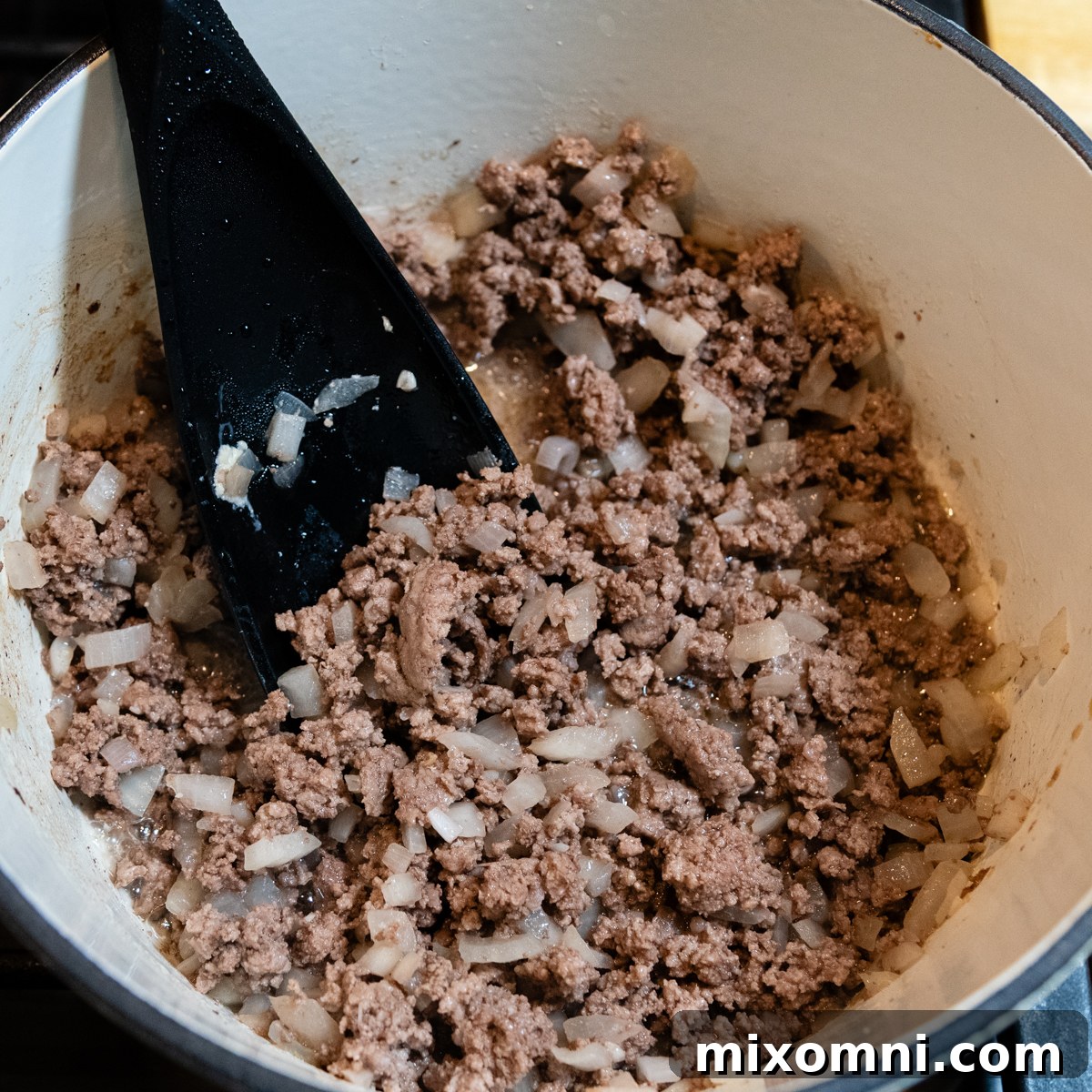 Cooked hamburger in a bowl with black spoon.