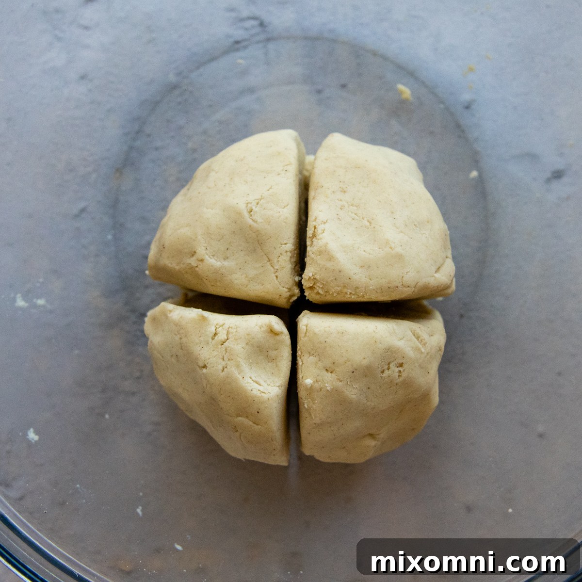 A large ball of tortilla dough cut into four even sections.