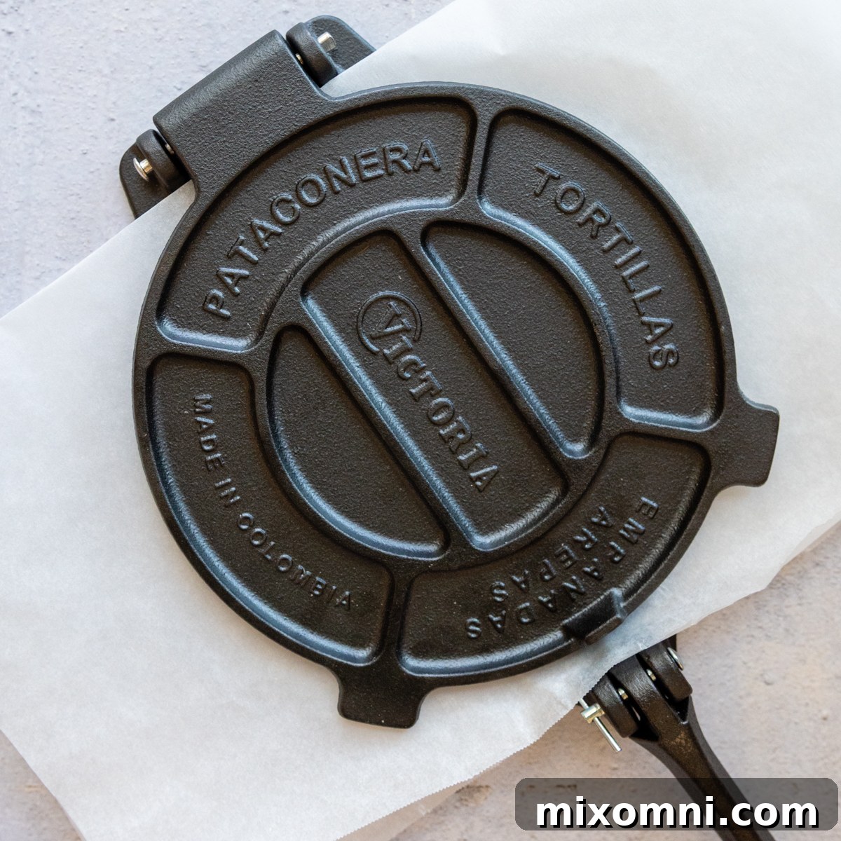 A tortilla press closed, actively pressing a dough ball into a flat tortilla.