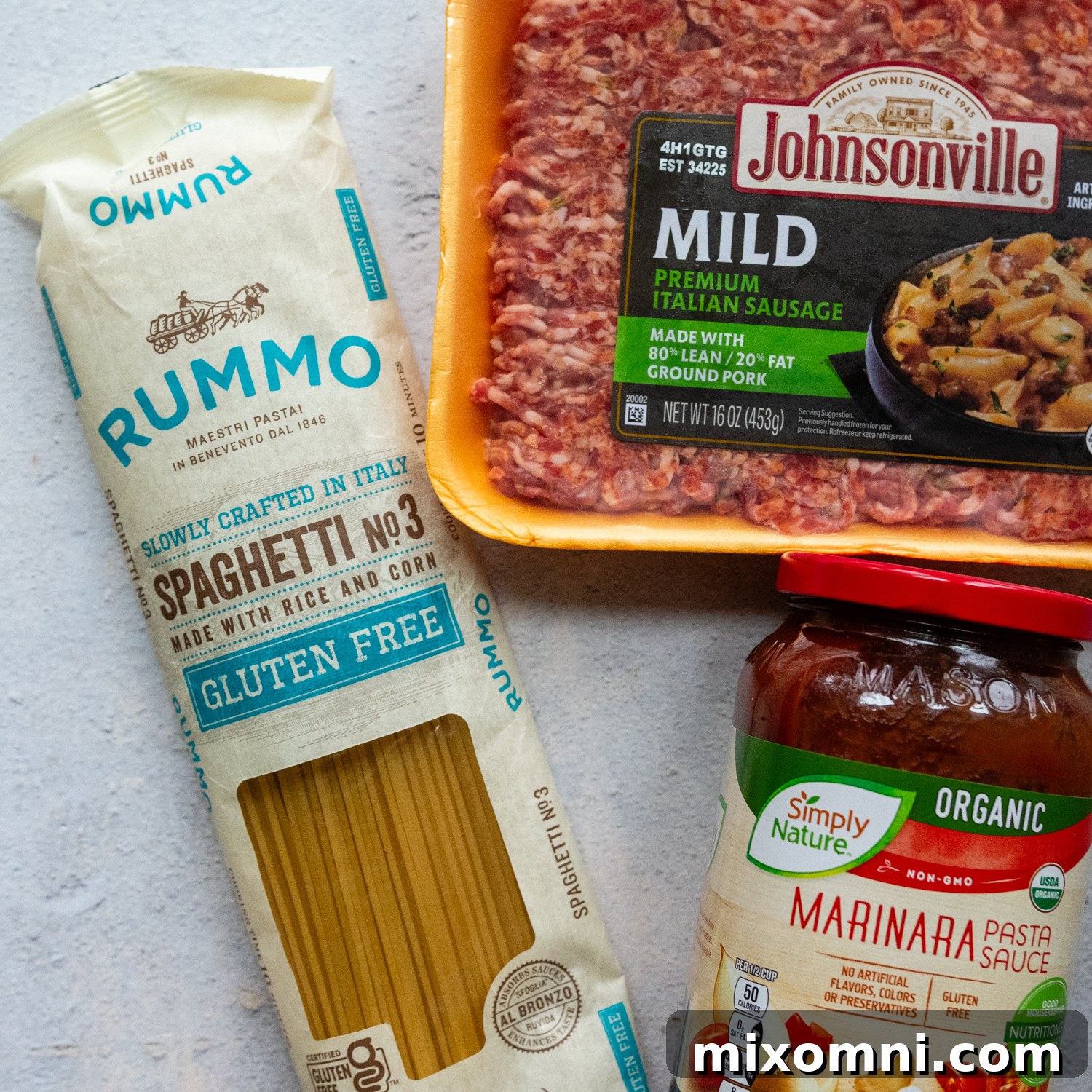 Various ingredients for gluten-free spaghetti bake, including gluten-free pasta, marinara sauce, cream cheese, Italian sausage, and mozzarella cheese.