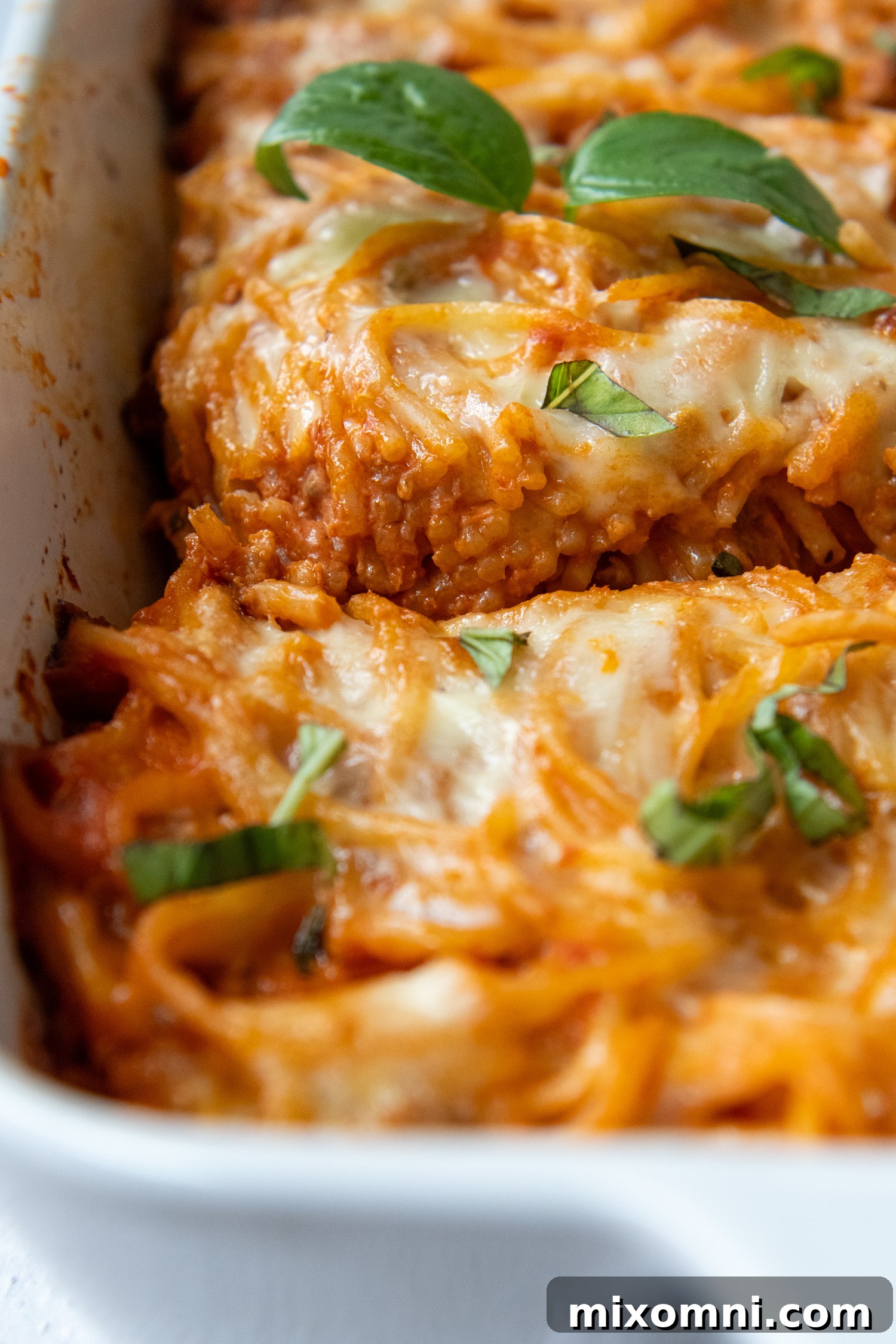 A full gluten-free spaghetti casserole, freshly baked and sliced into neat portions, served in a white baking dish.