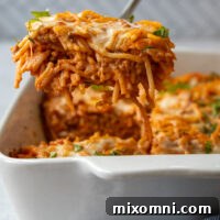 Overhead shot of a piece casserole being lifted out of baking dish by a utensil.