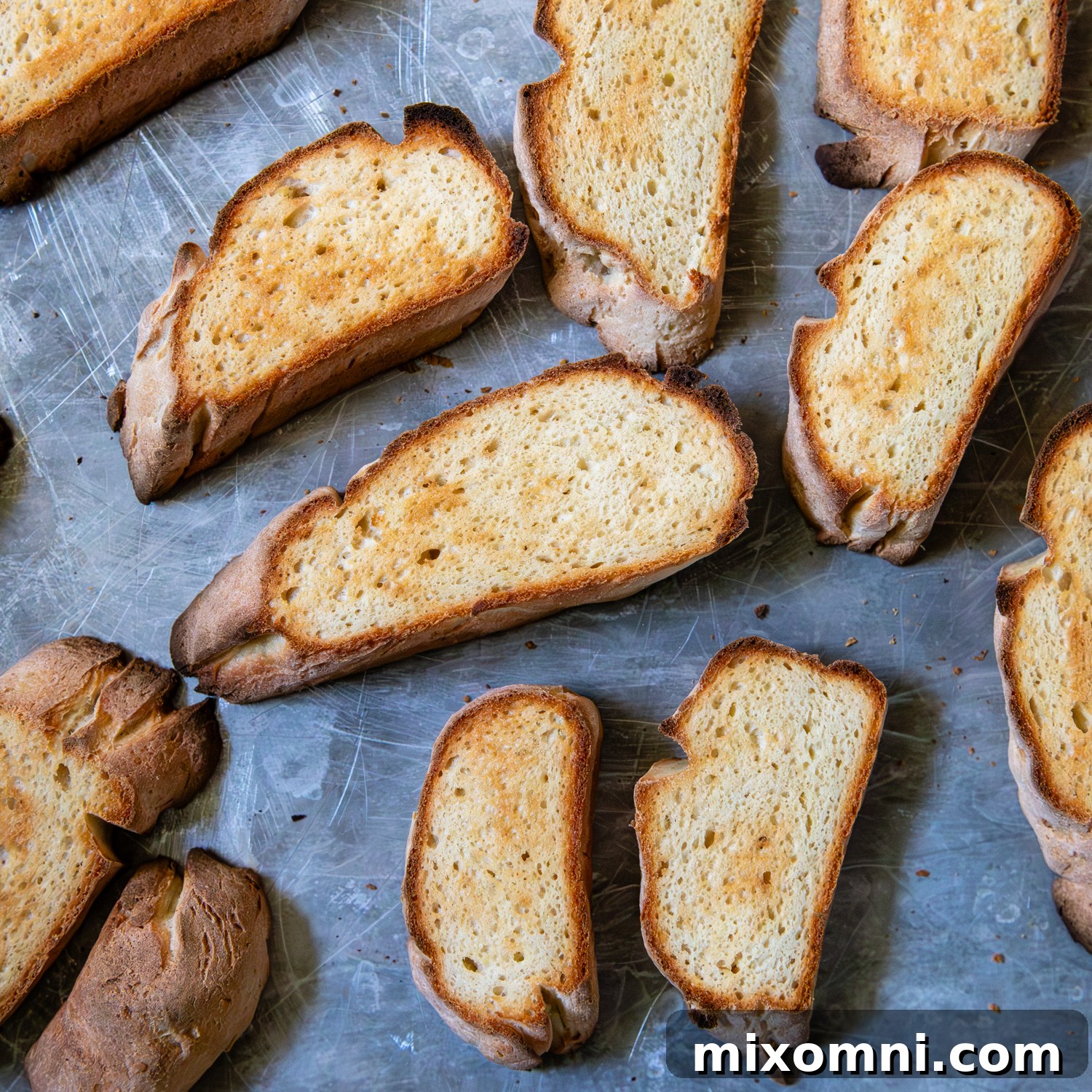 Toasted slices of gluten-free French bread arranged neatly on a baking sheet, golden and ready for soup topping.