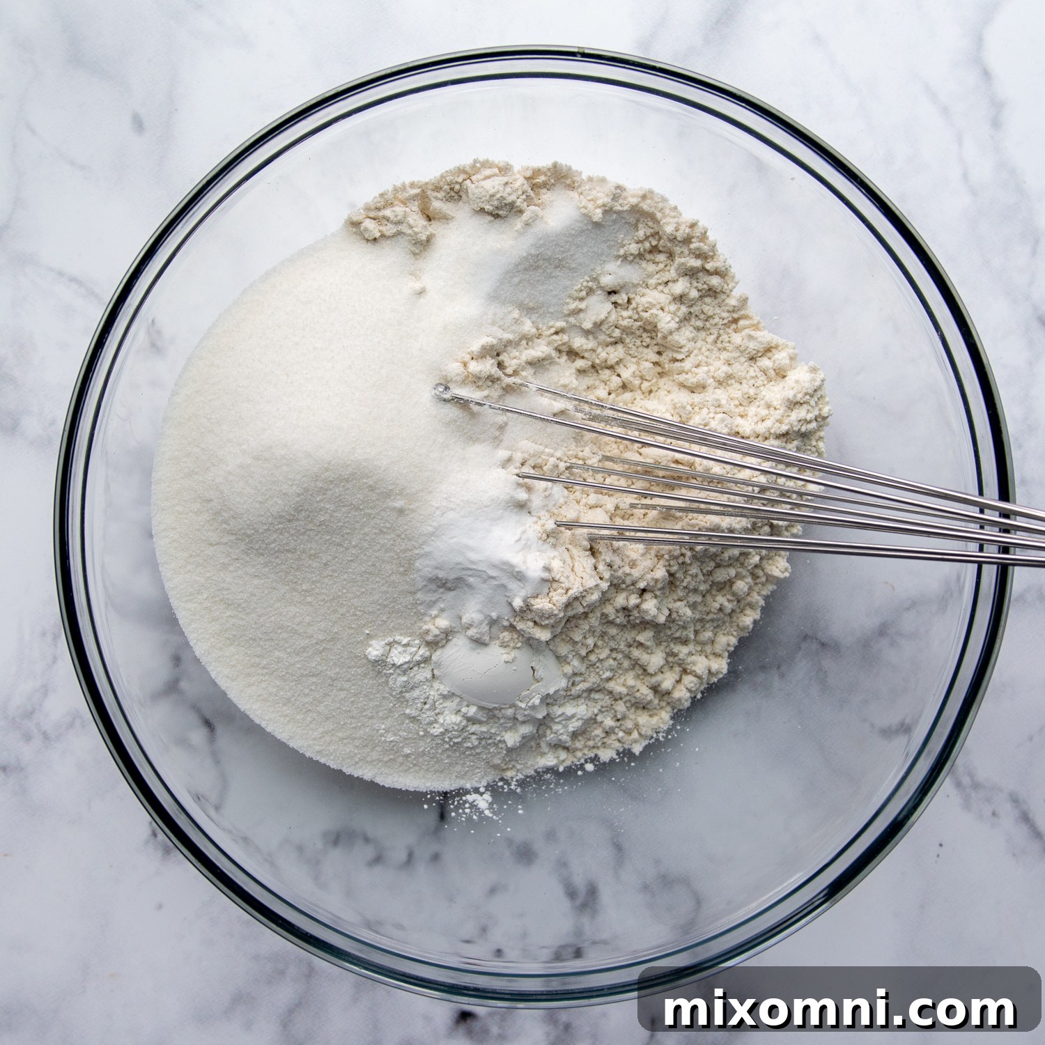 Dry ingredients being mixed in a glass bowl.