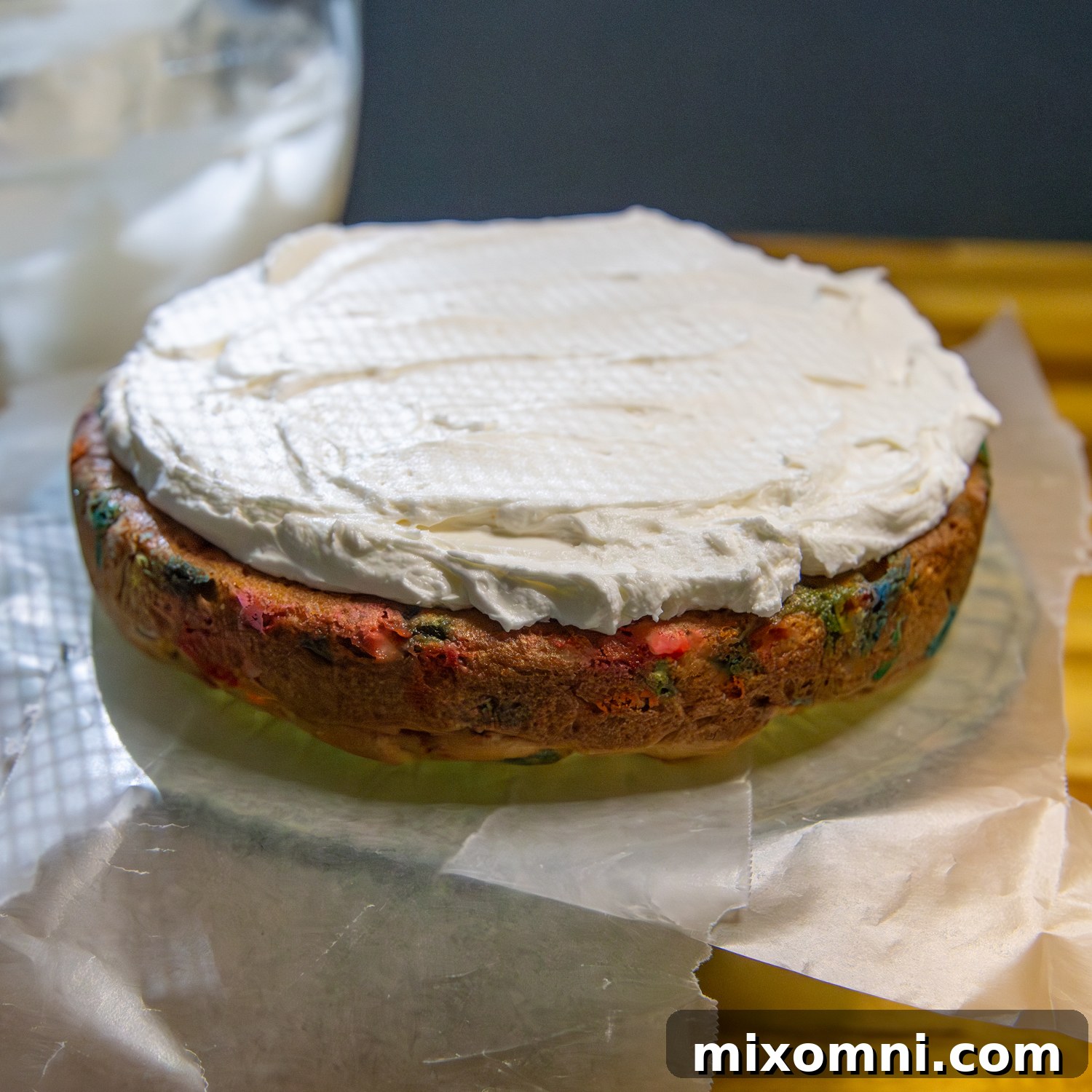 Cake on parchment paper being frosted