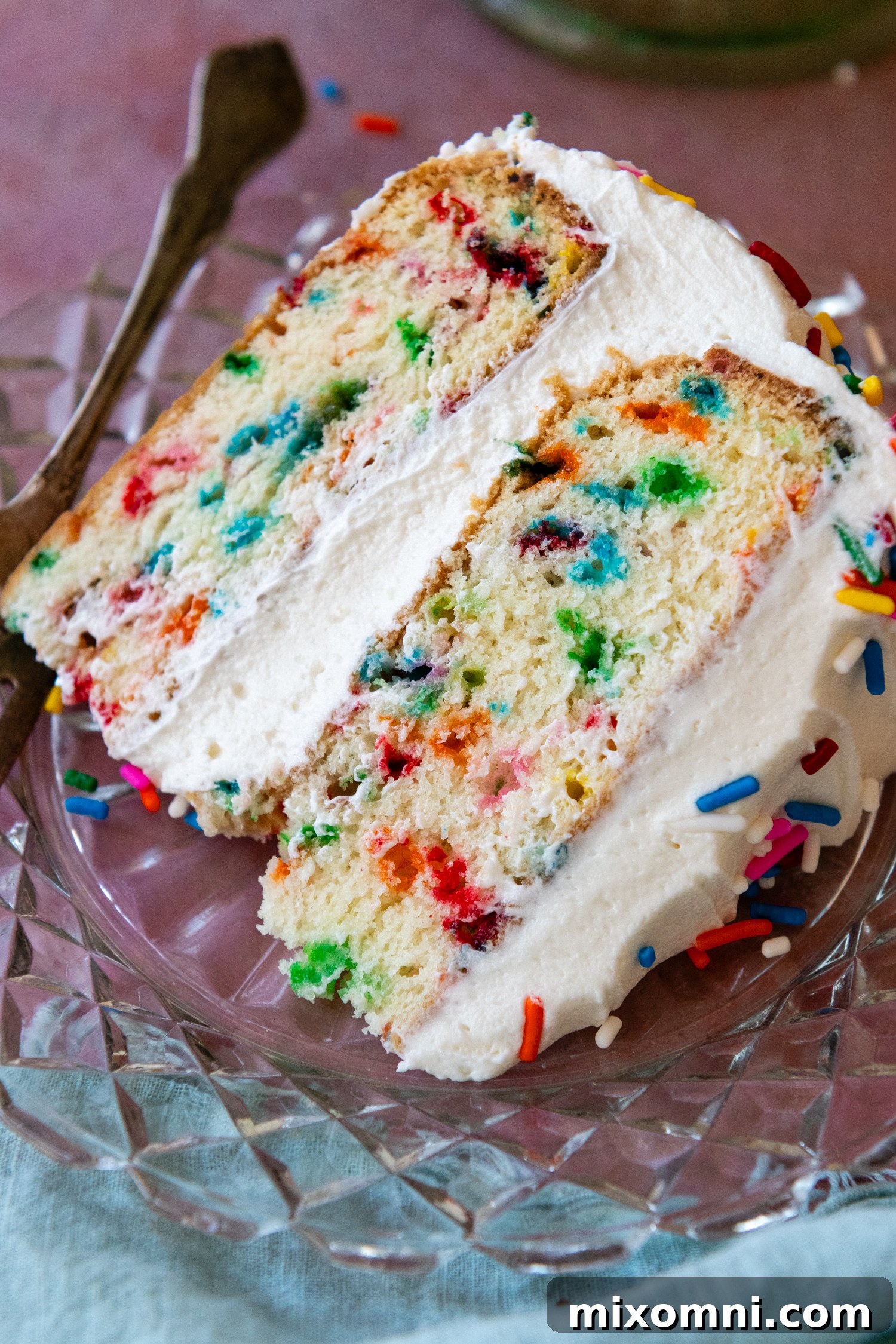 Overhead shot of a perfect slice of gluten-free funfetti cake on a glass plate.