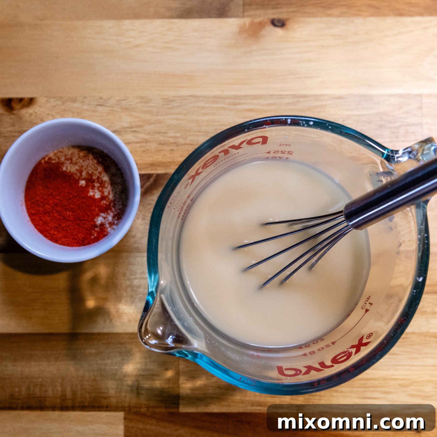 Liquid ingredients being whisked in a glass measuring cup.