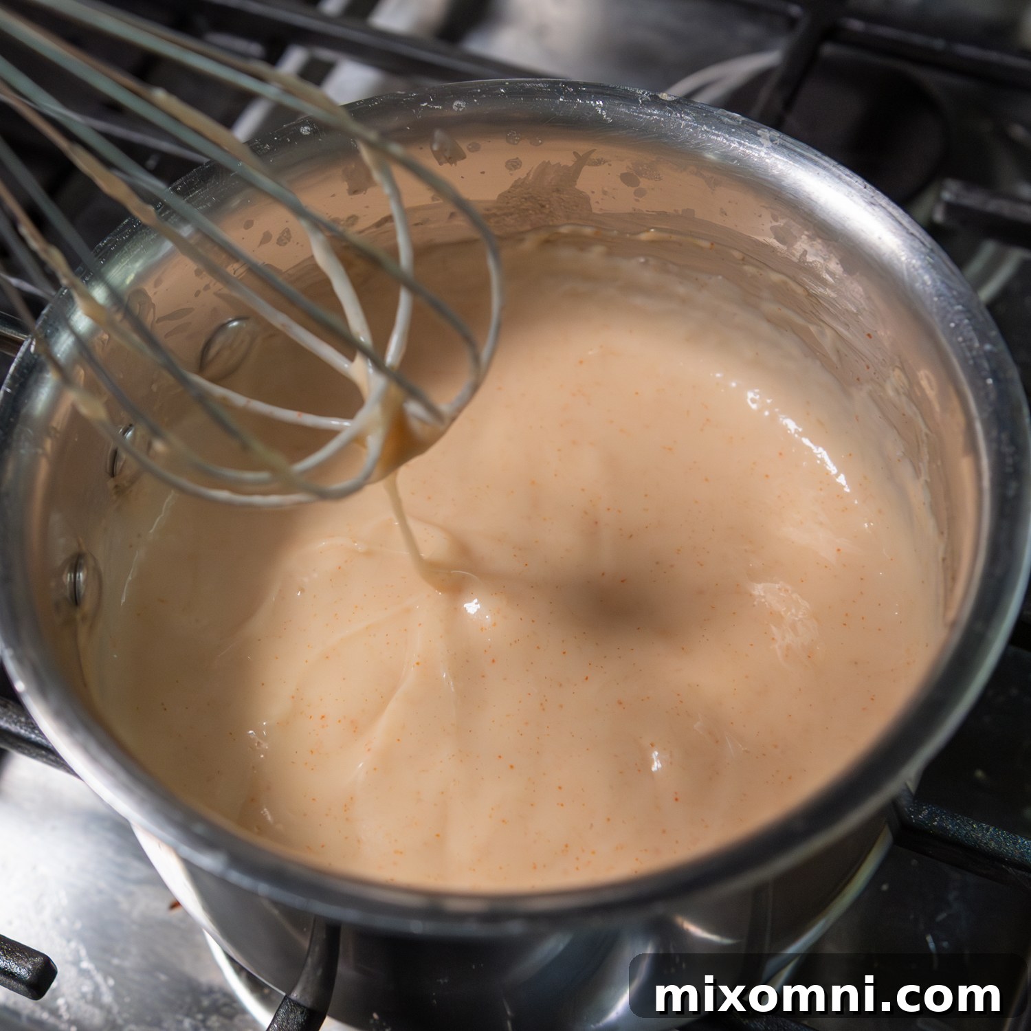 Creamy sauce being whisked in a pot.