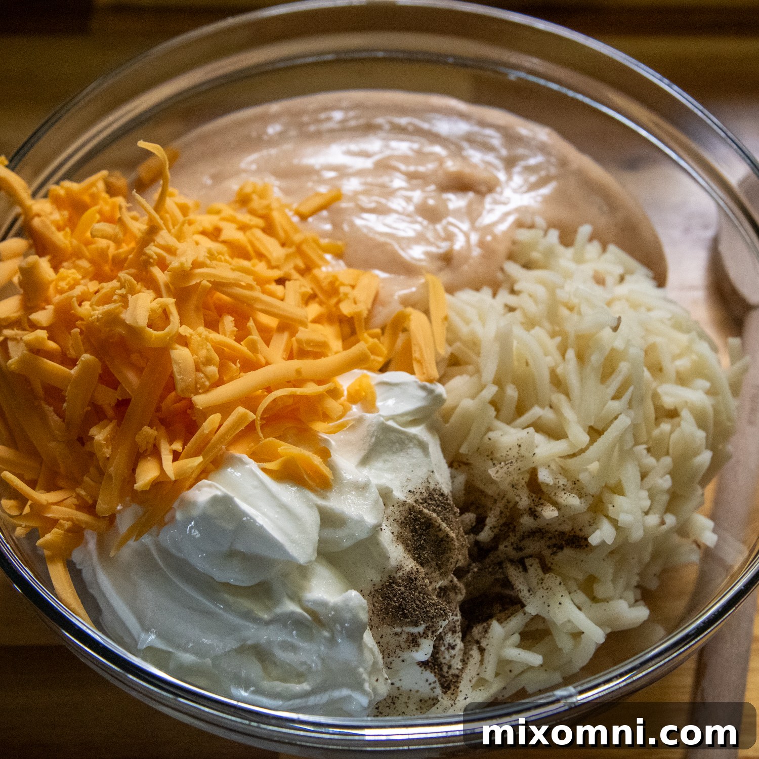 Shredded cheese, sour cream and hash browns being added to cream sauce.
