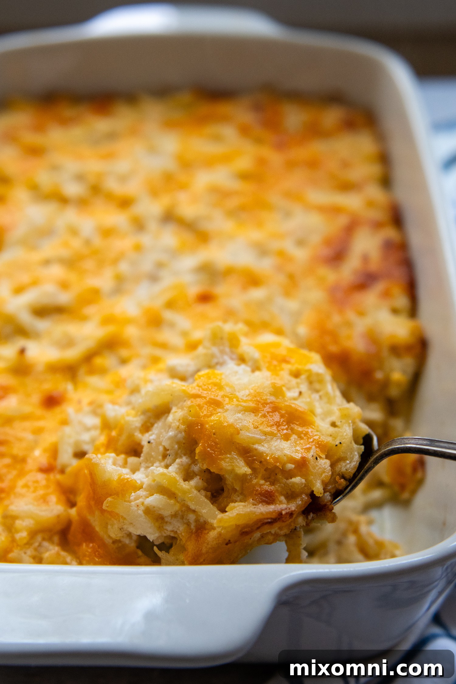 Casserole in a white baking dish with a serving being lifted out by a spoon.