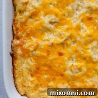 Cheesy gluten free hash brown casserole in a white baking dish.