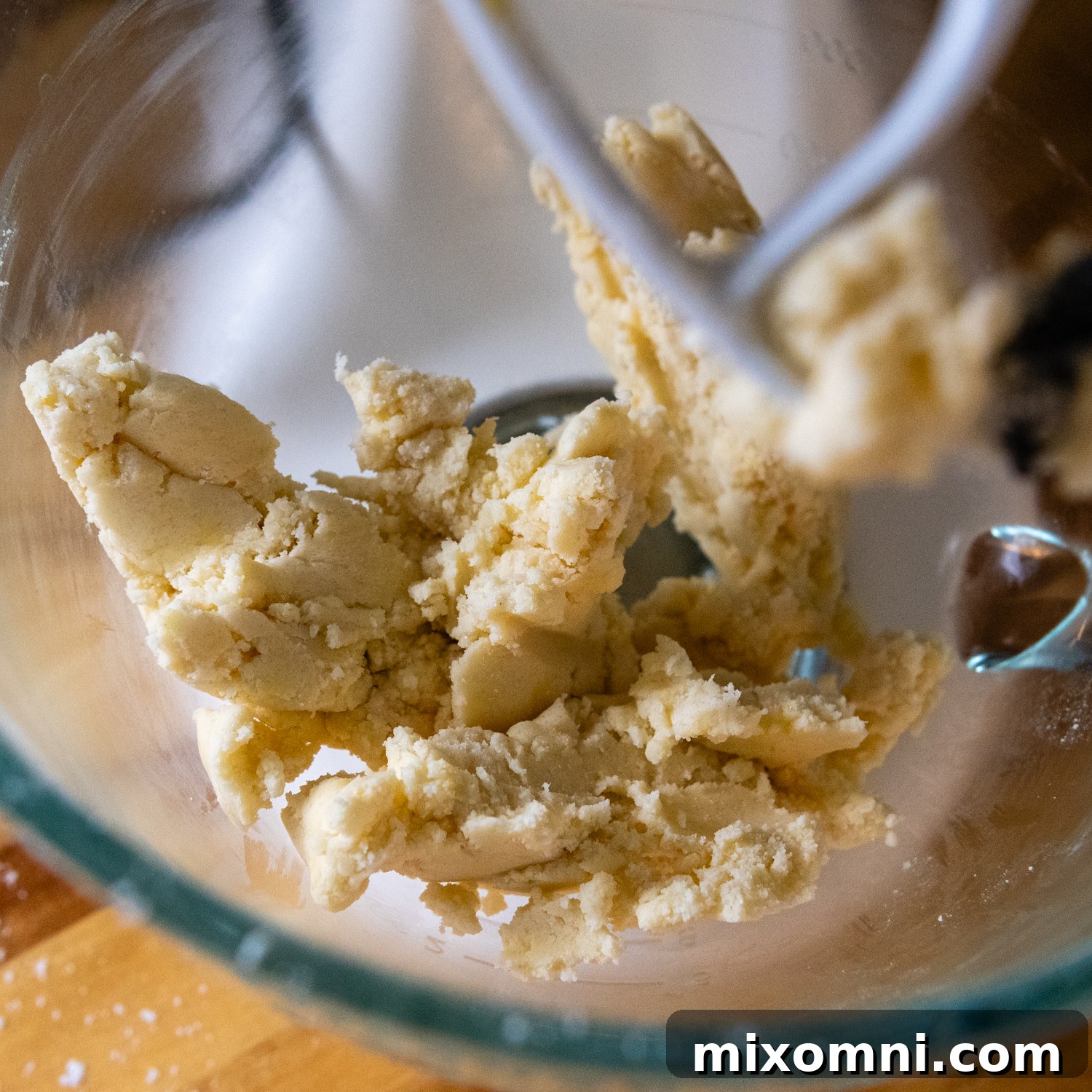 Soft shortbread dough in a glass mixing bowl after egg yolk has been added.