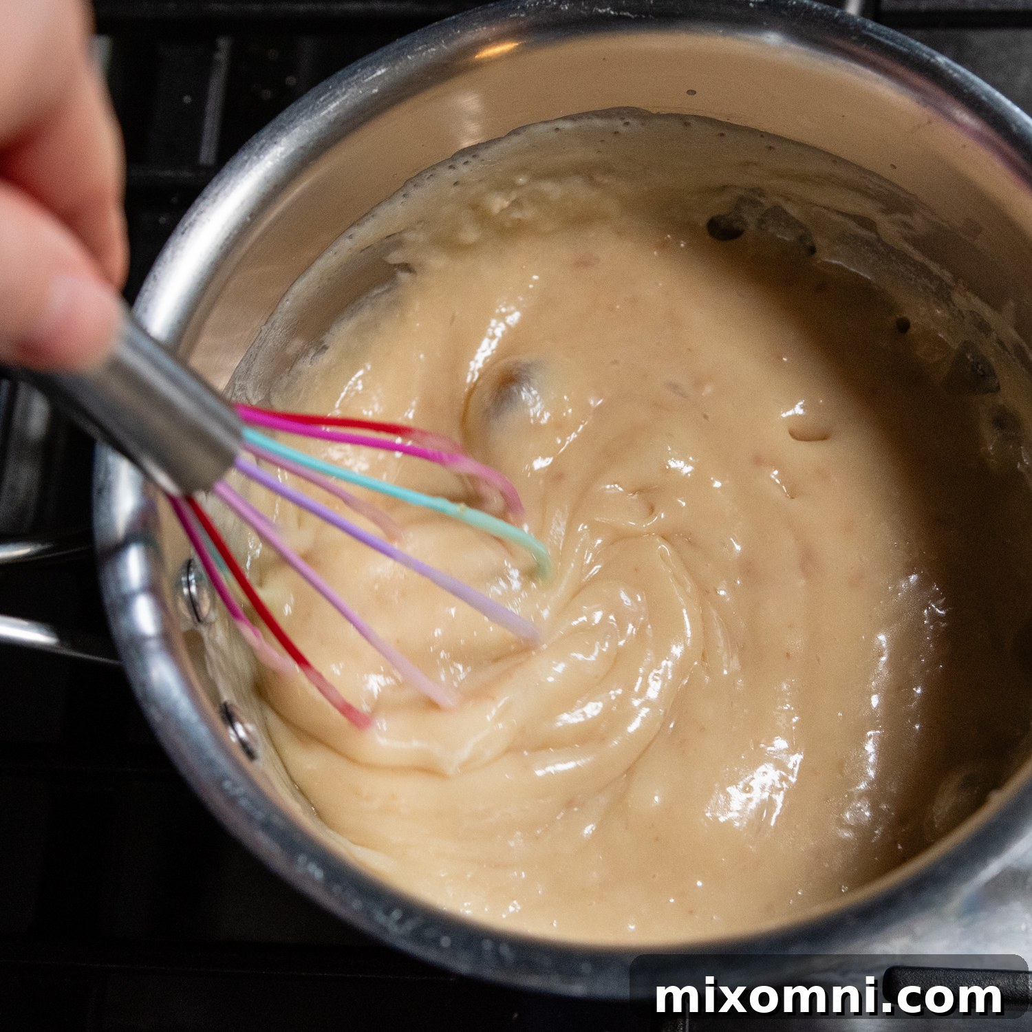 Caramel mixture being whisked in a saucepan, showing its smooth texture.