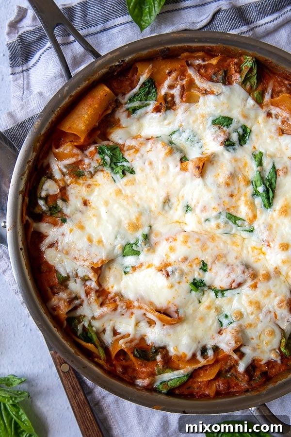 overhead shot of skillet lasagna in a stainless steel pan with fresh basil scattered around