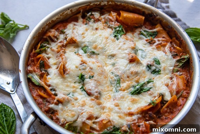 landscape image of one pan lasagna with melted cheese and spinach on top